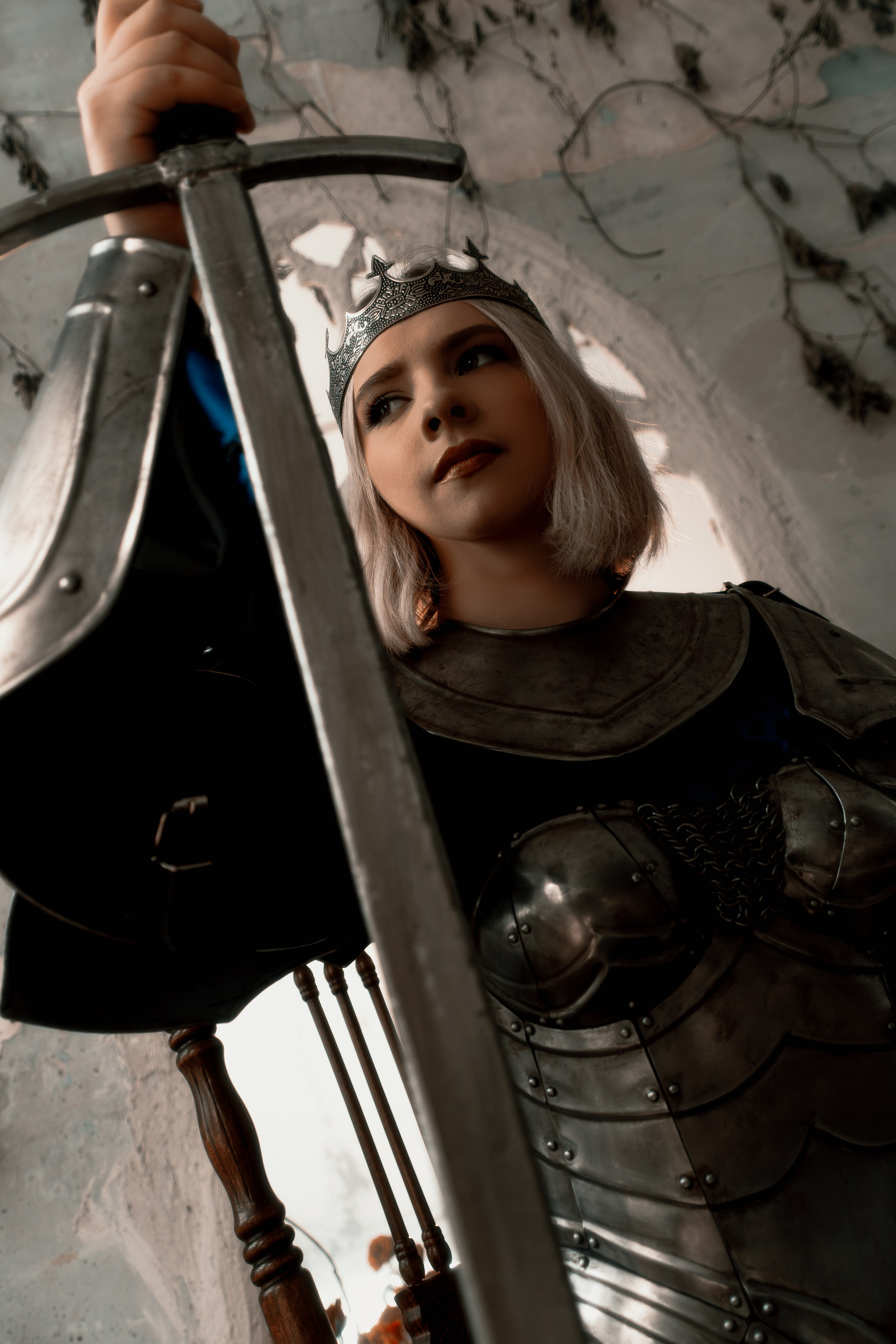 Великолепный студийный портрет девушки в блестящих рыцарских доспехах. Профессиональное освещение подчеркивает фактуру металла и красоту модели.