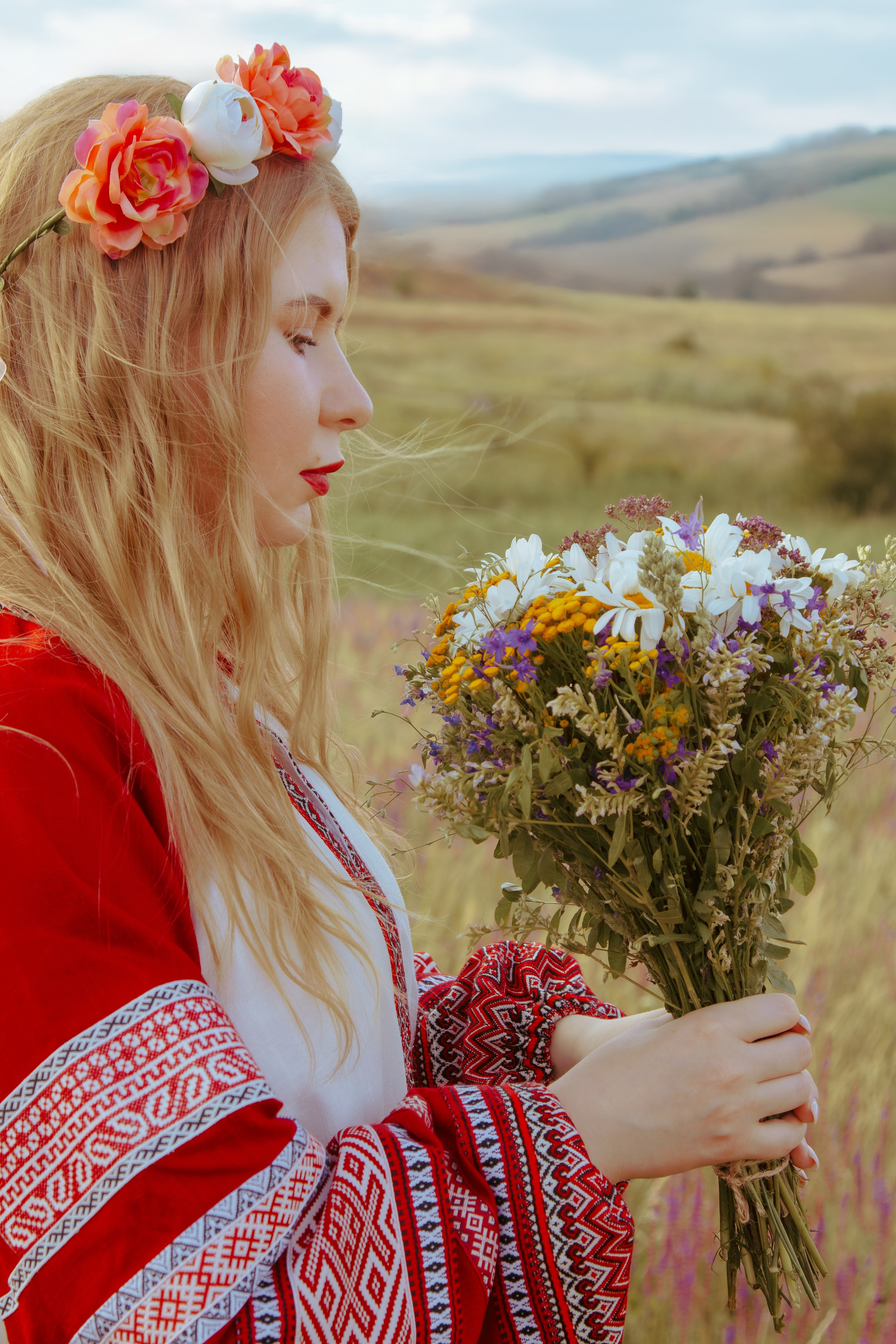 Девушка держит цветы в руках в славянской одежде 