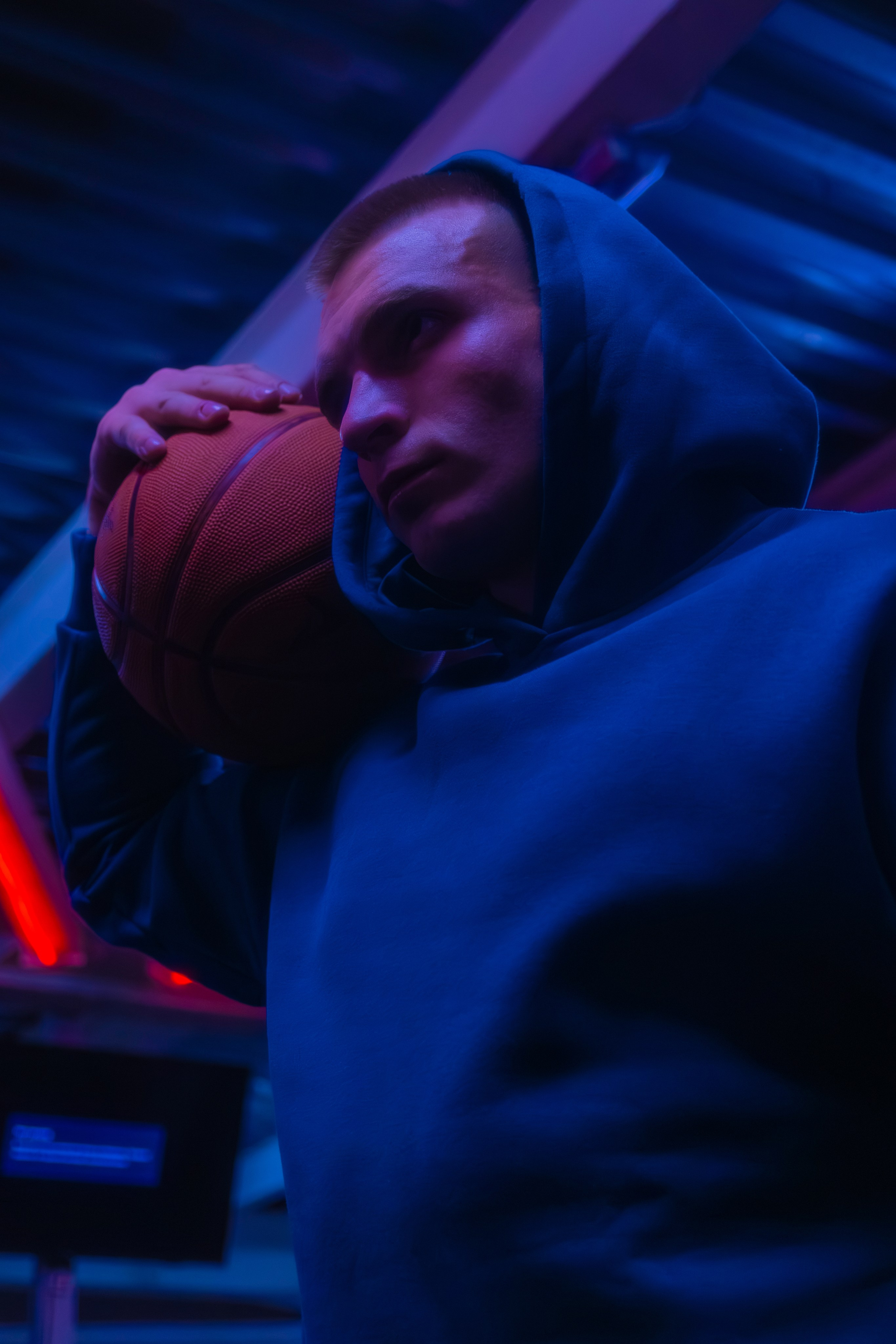 Изысканный портрет спортивного тренера в современном зале, где неоновое освещение создает завораживающий контраст с рельефными мышцами.