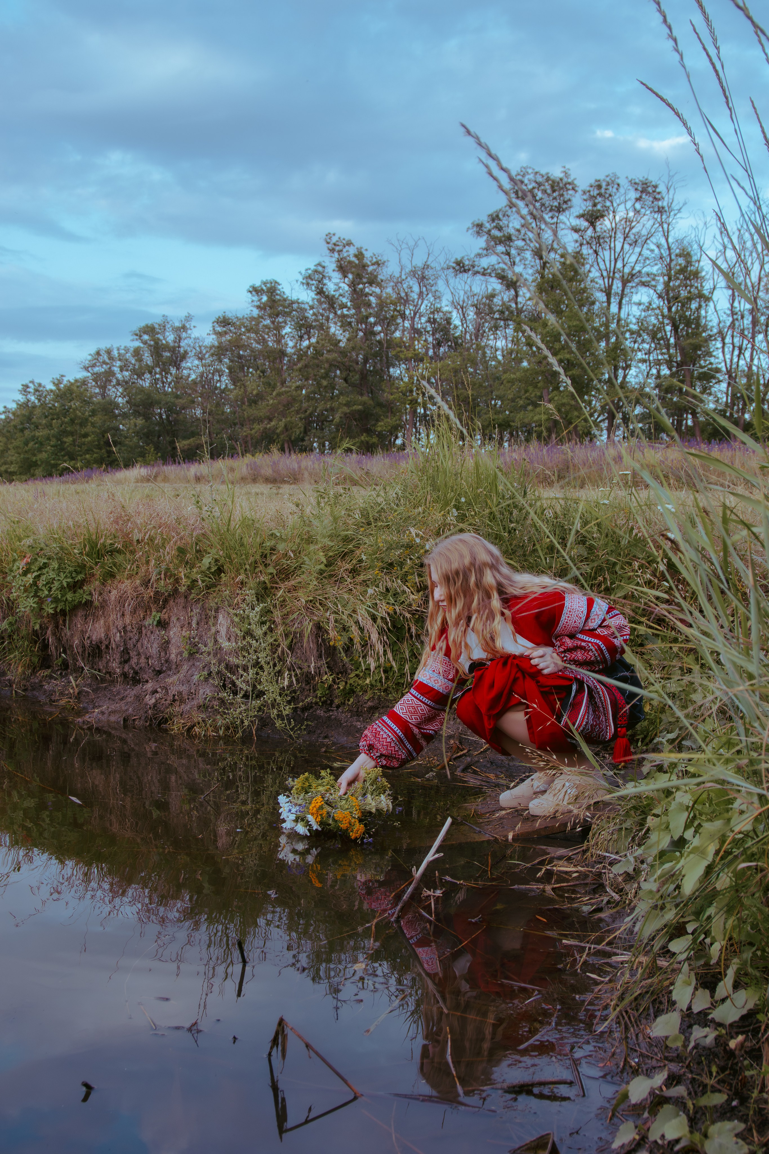 Славянская девушка отпускает венок в воду, чтя народные традиции 