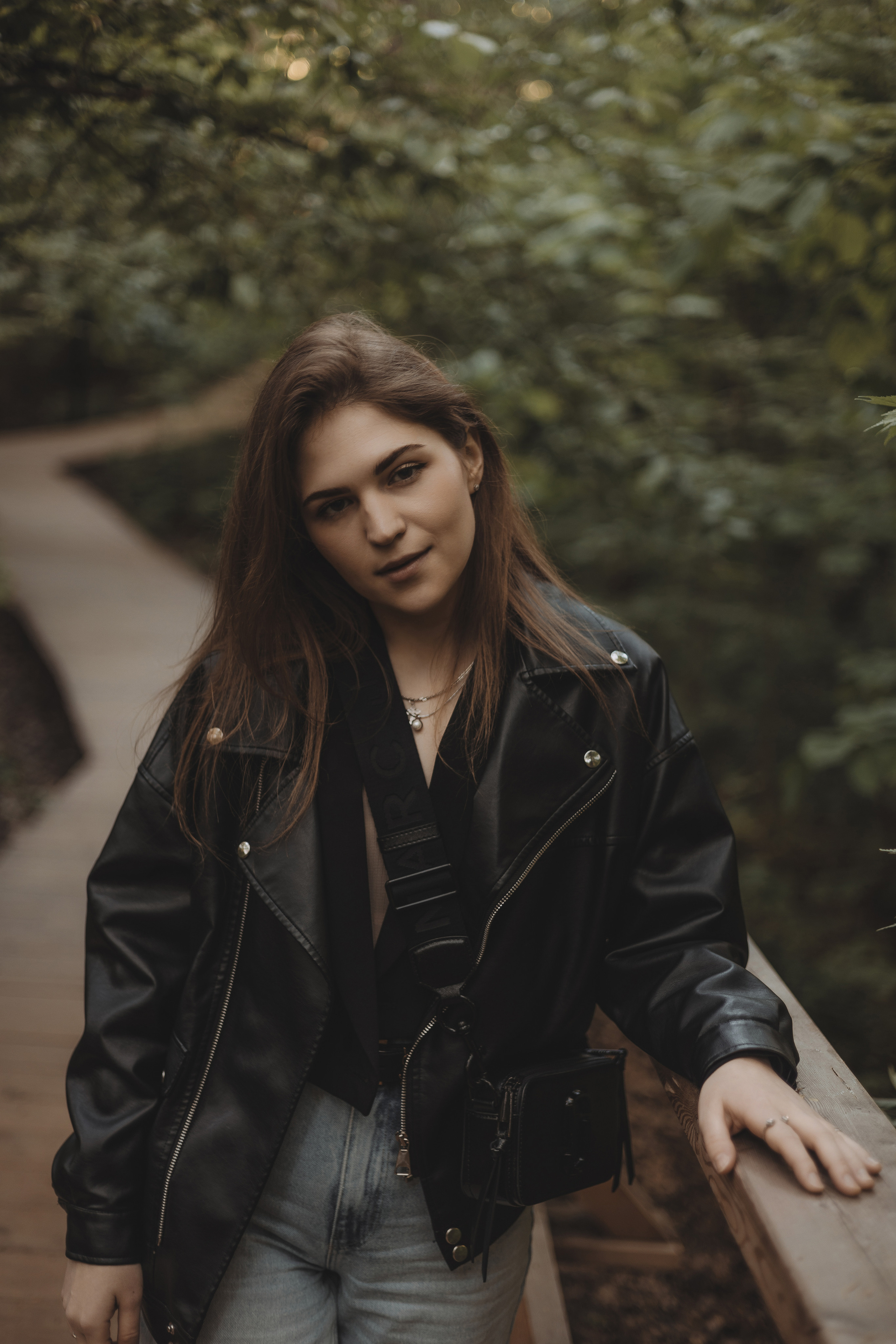 уличная фотосессия в лесу, девушка в кожанке смотрит в камеру