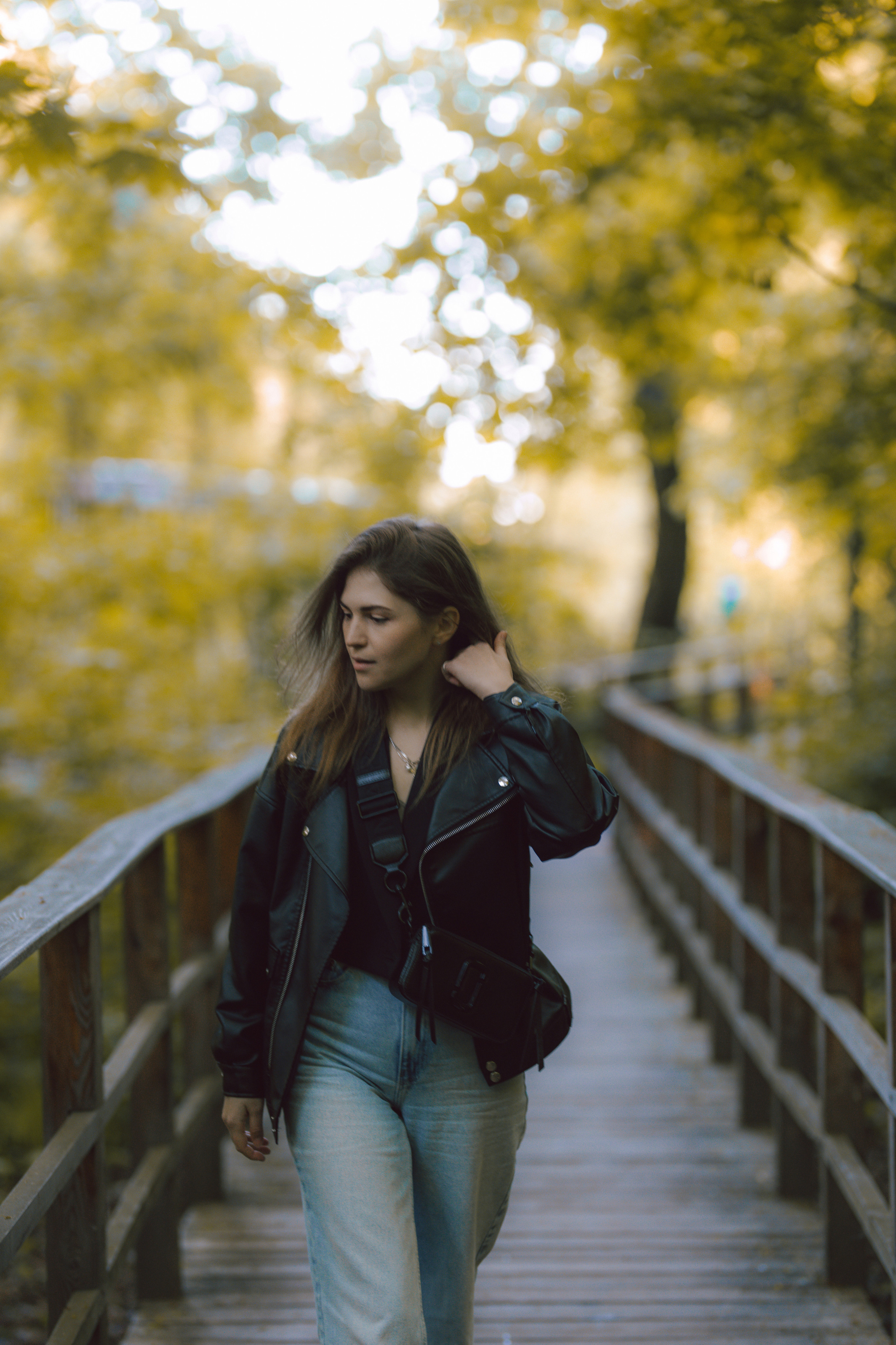 осенняя фотосессия в парке, девушка в кожанке сидит на мосту