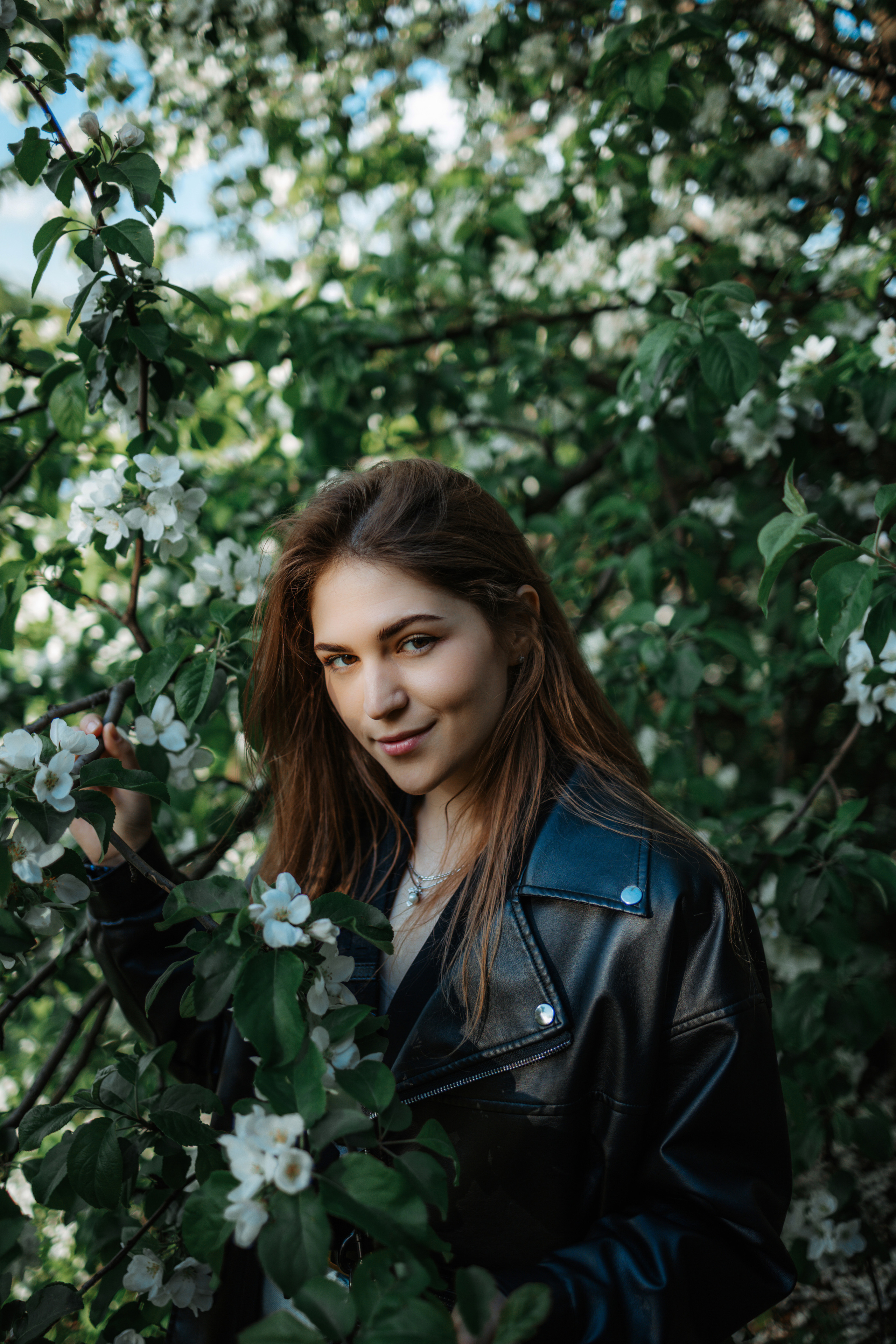 девушка в кожанке на фоне зелёных деревьев, портретная съёмка