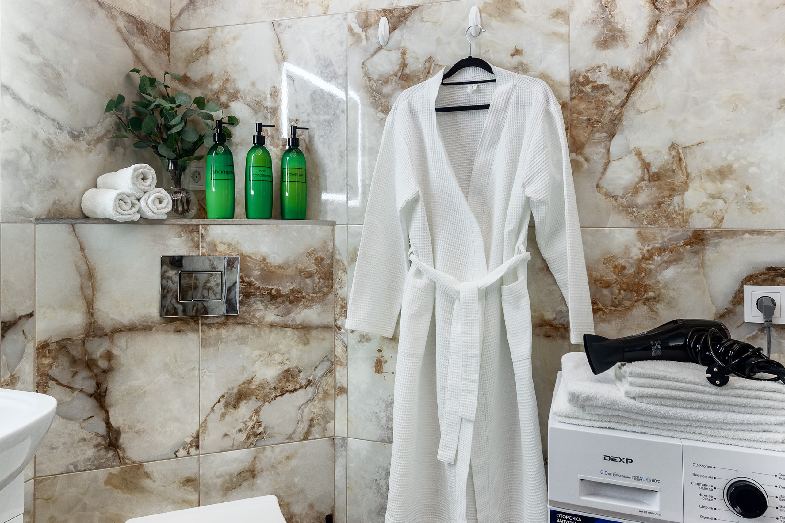 Белый халат, висящий на стене в ванной комнате