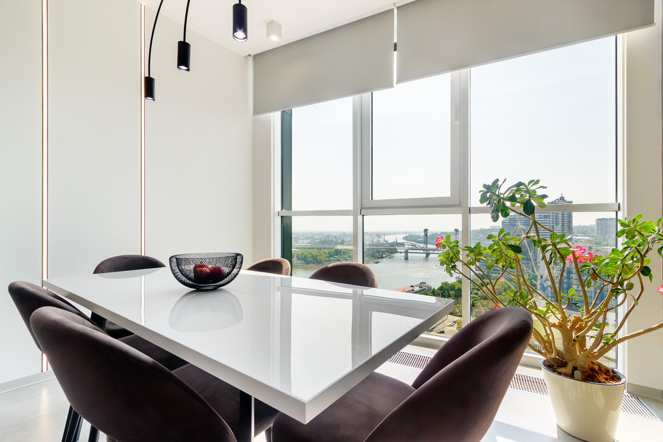 Большой обеденный стол, стоящий рядом с панорамными окнами, в квартире с видом на реку Дон в г. Ростов-на-Дону