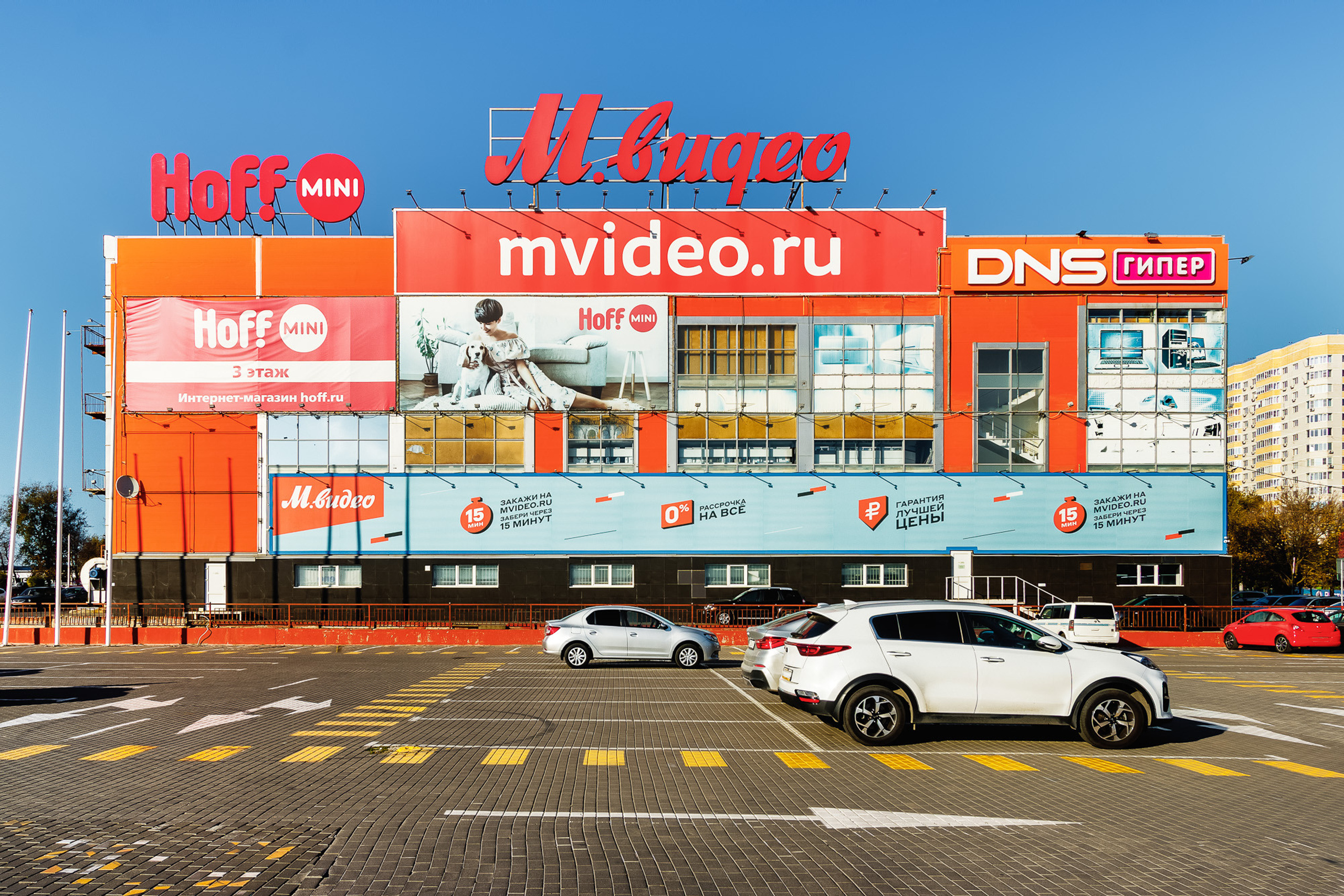 Многоэтажное здание торгового центра с парковкой перед ним