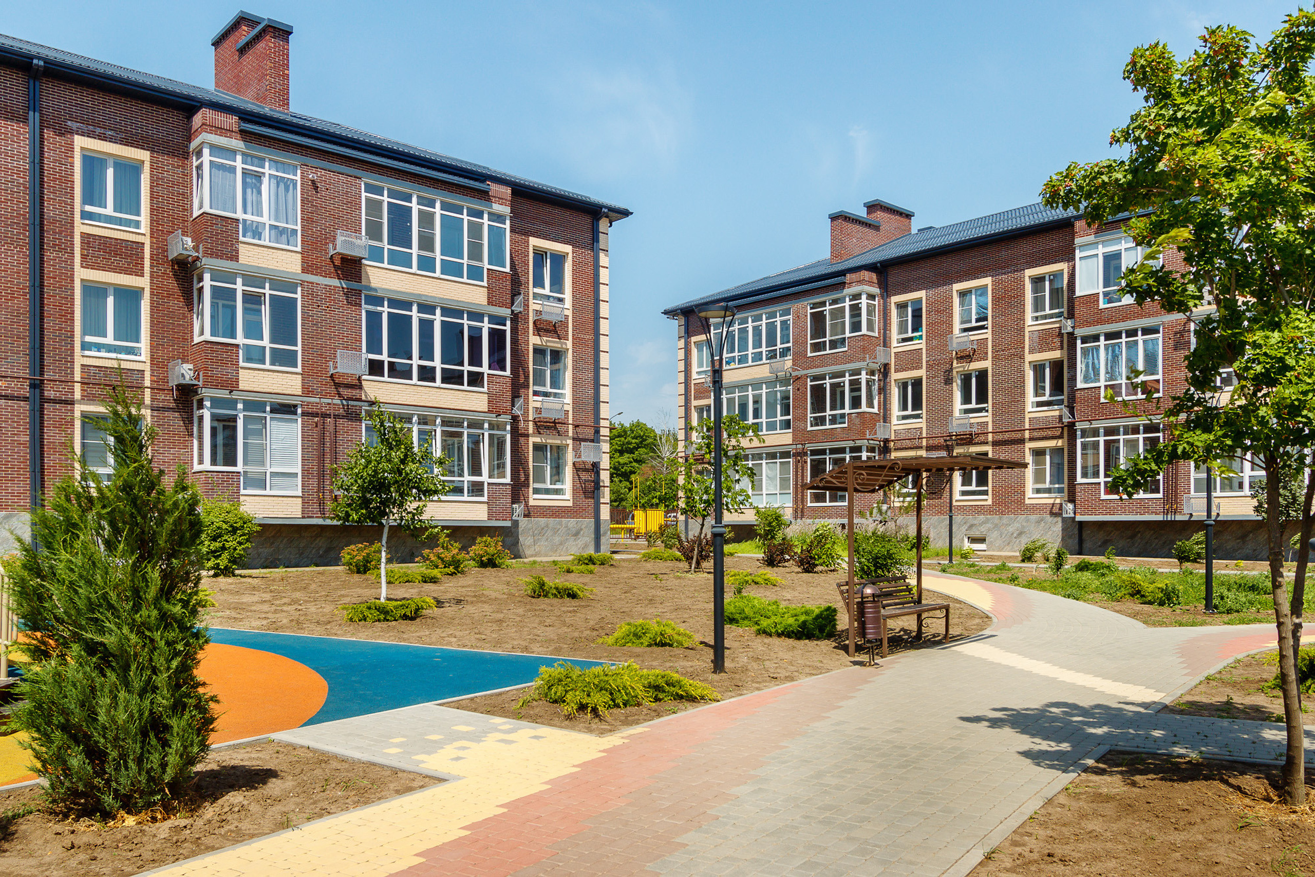 Зона отдыха с дорожками и лавочками в жилом комплексе, состоящем из трёхэтажных зданий