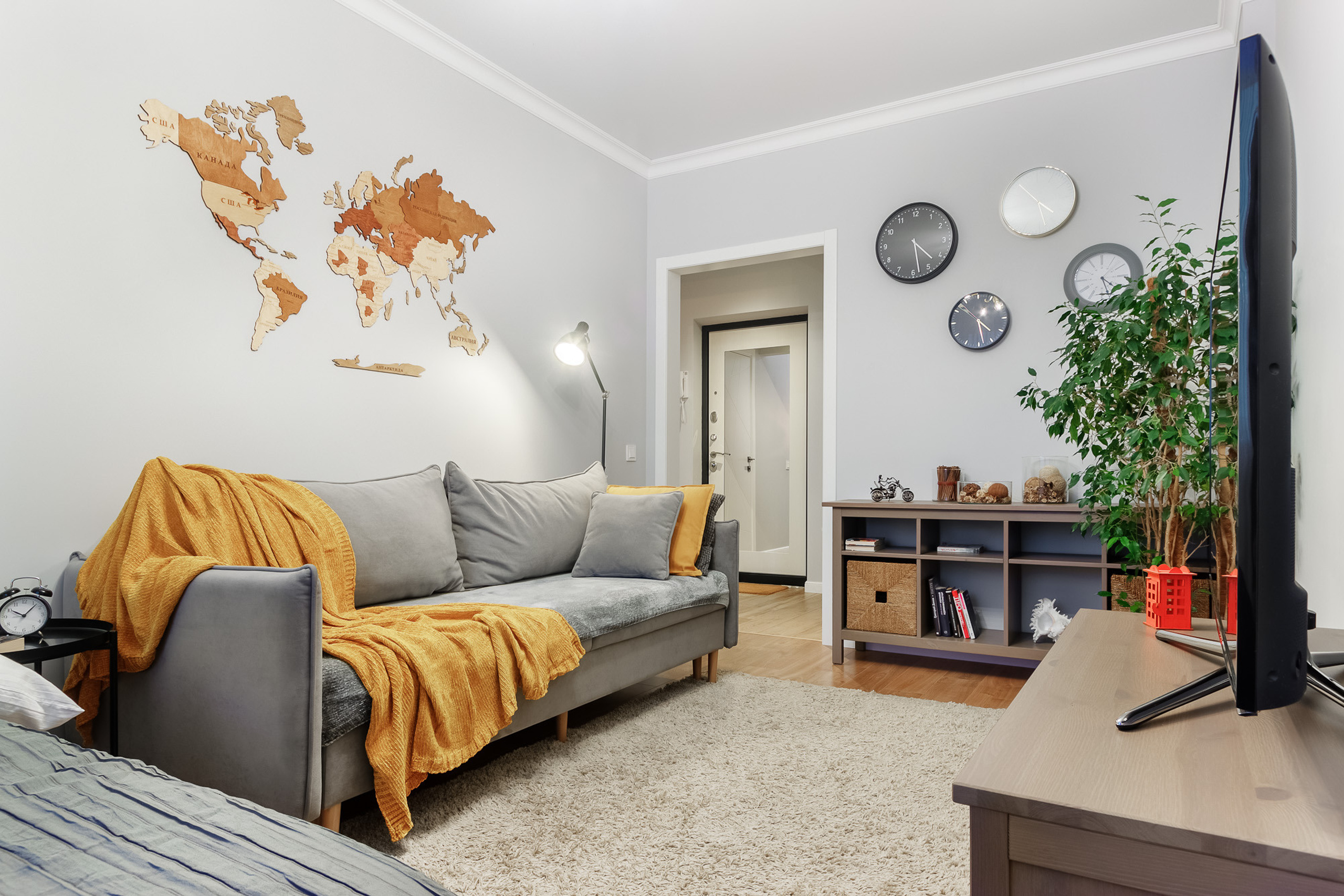 Современный светло-серый интерьер гостиной с деревянной картой мира на стене