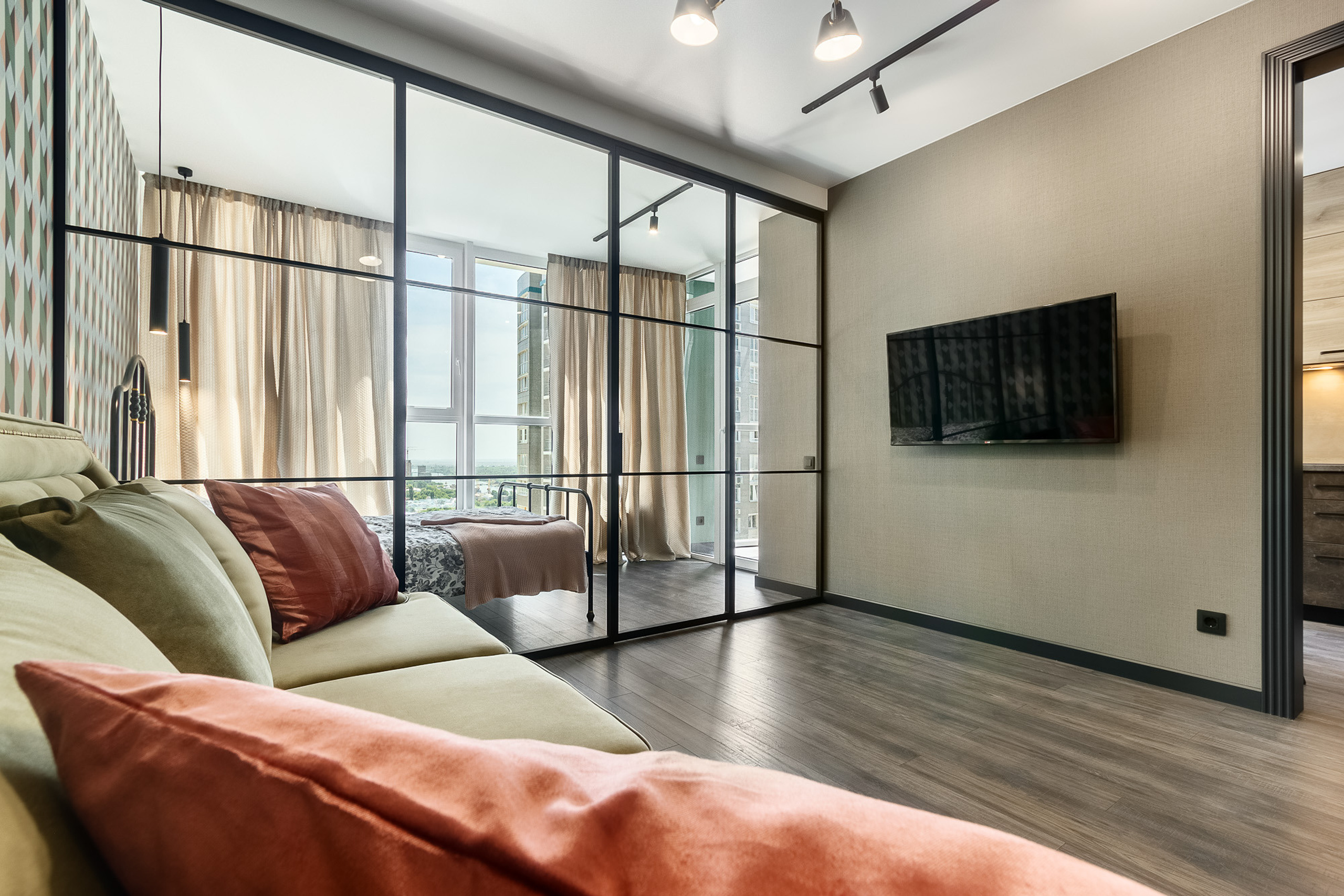 Фотография интерьера квартиры в графитовых тонах со стеклянной перегородкой между гостиной и спальней