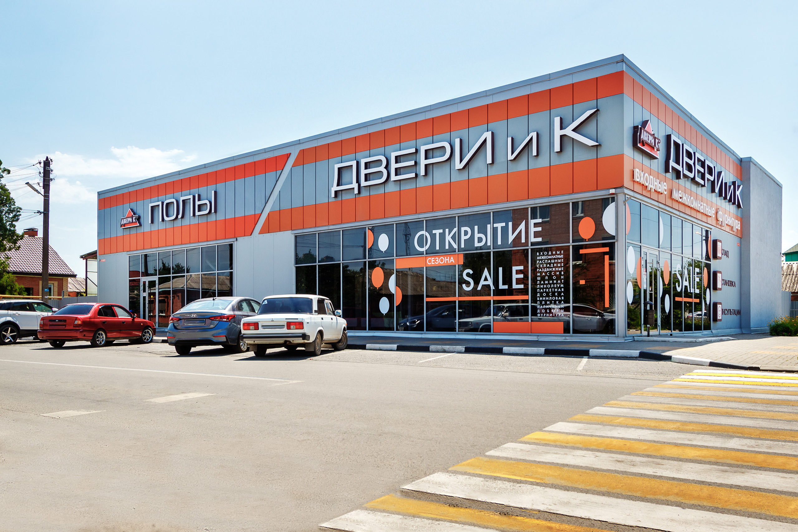 Фасад магазина, продающего двери, с расположенной перед ним парковкой