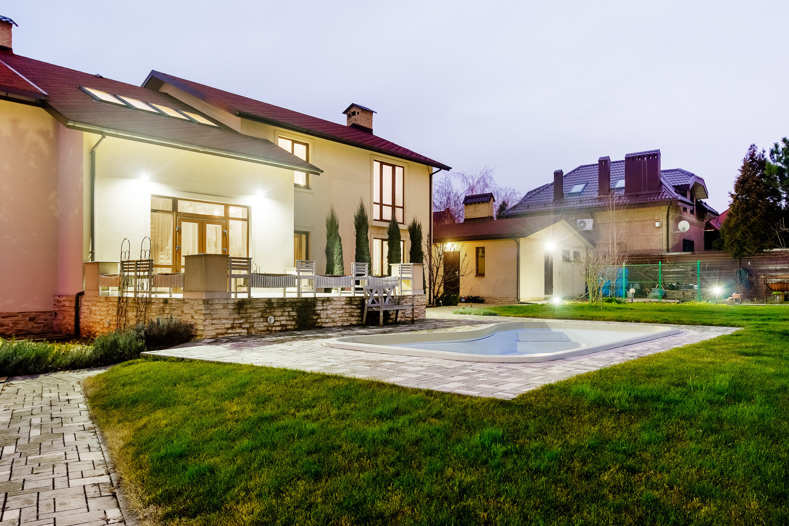 Задний двор загородного дома с бассейном, сфотографированный в вечернее время