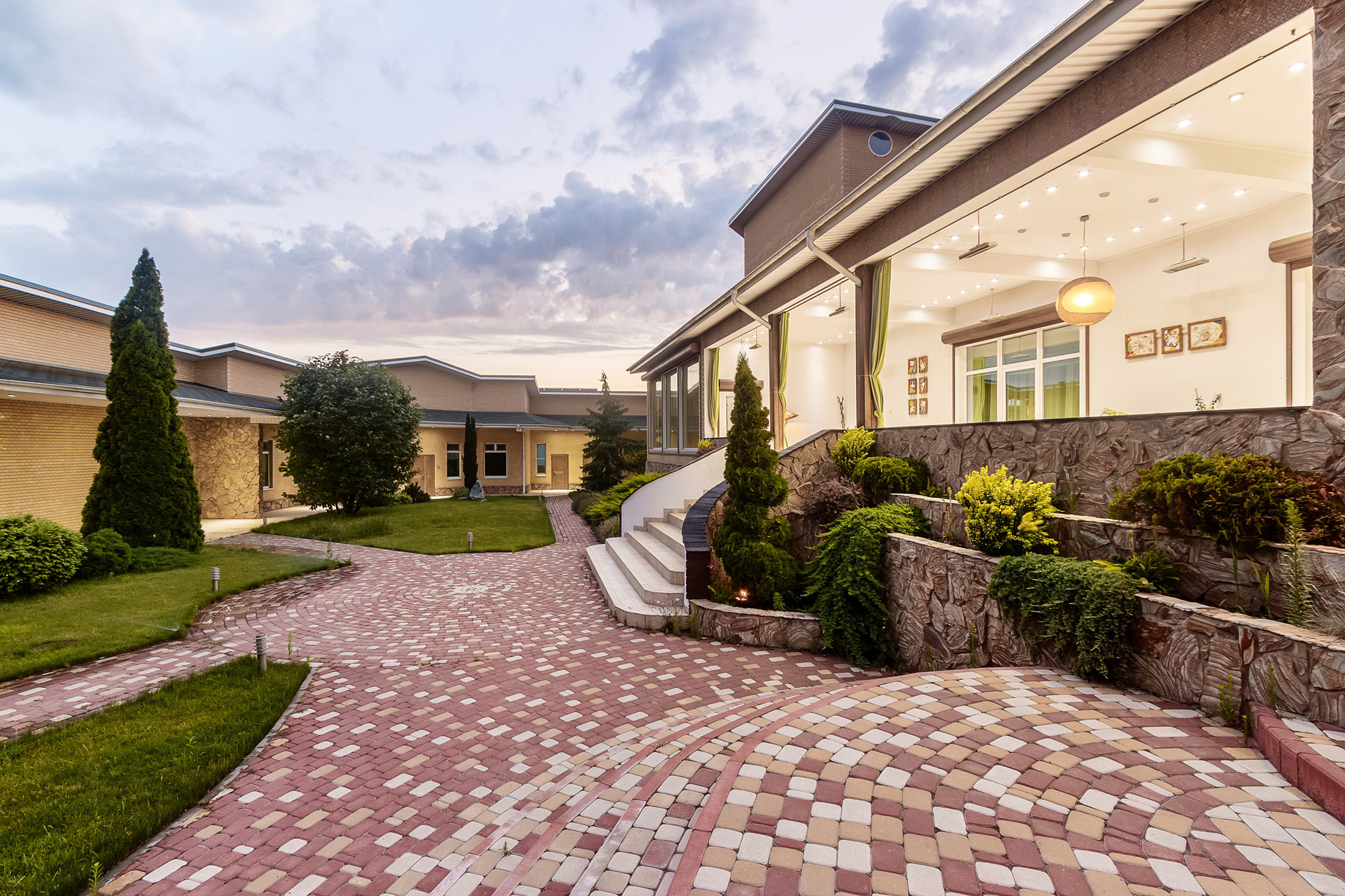 Двор и летняя веранда большого загородного дома, сфотографированные в вечернее время