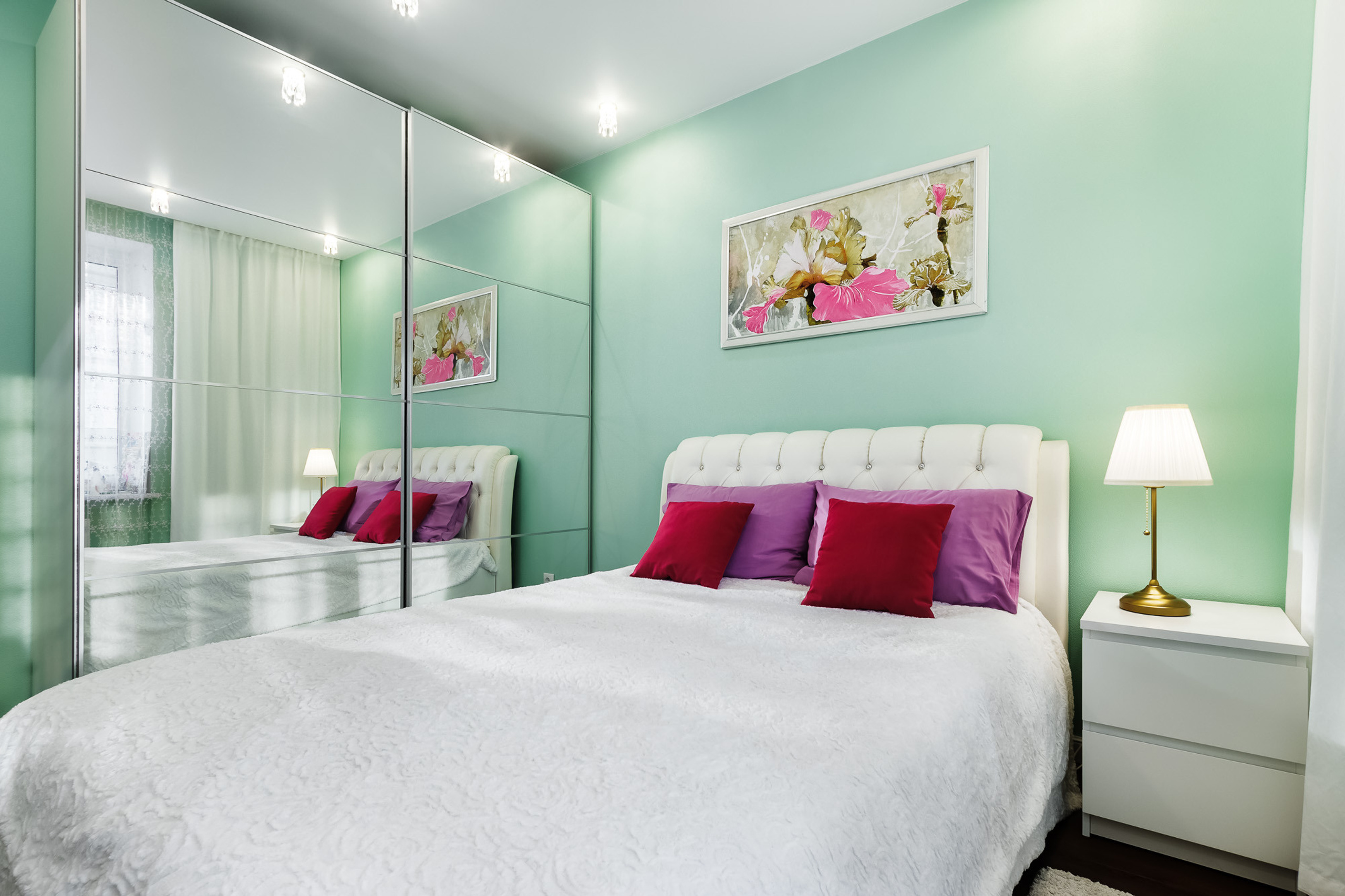 Интерьер спальни, оформленной в белом, зелёном и красном цветах