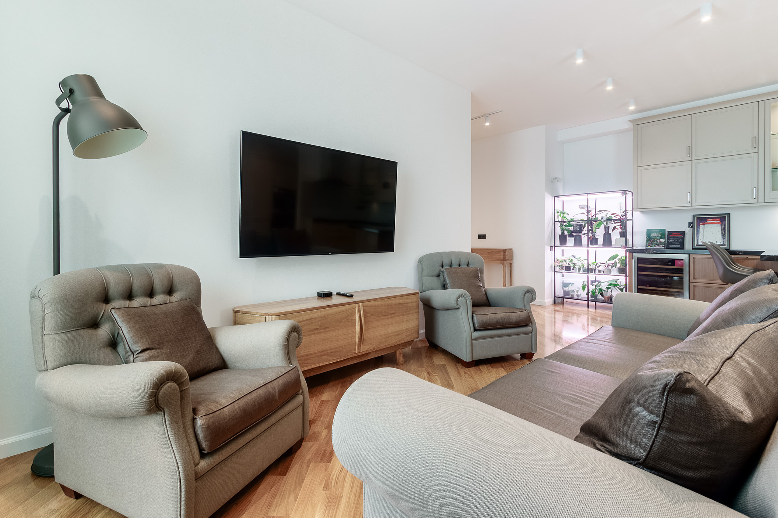 Зона отдыха с диваном и двумя креслами в большой квартире. Интерьер в серых и коричневых тонах