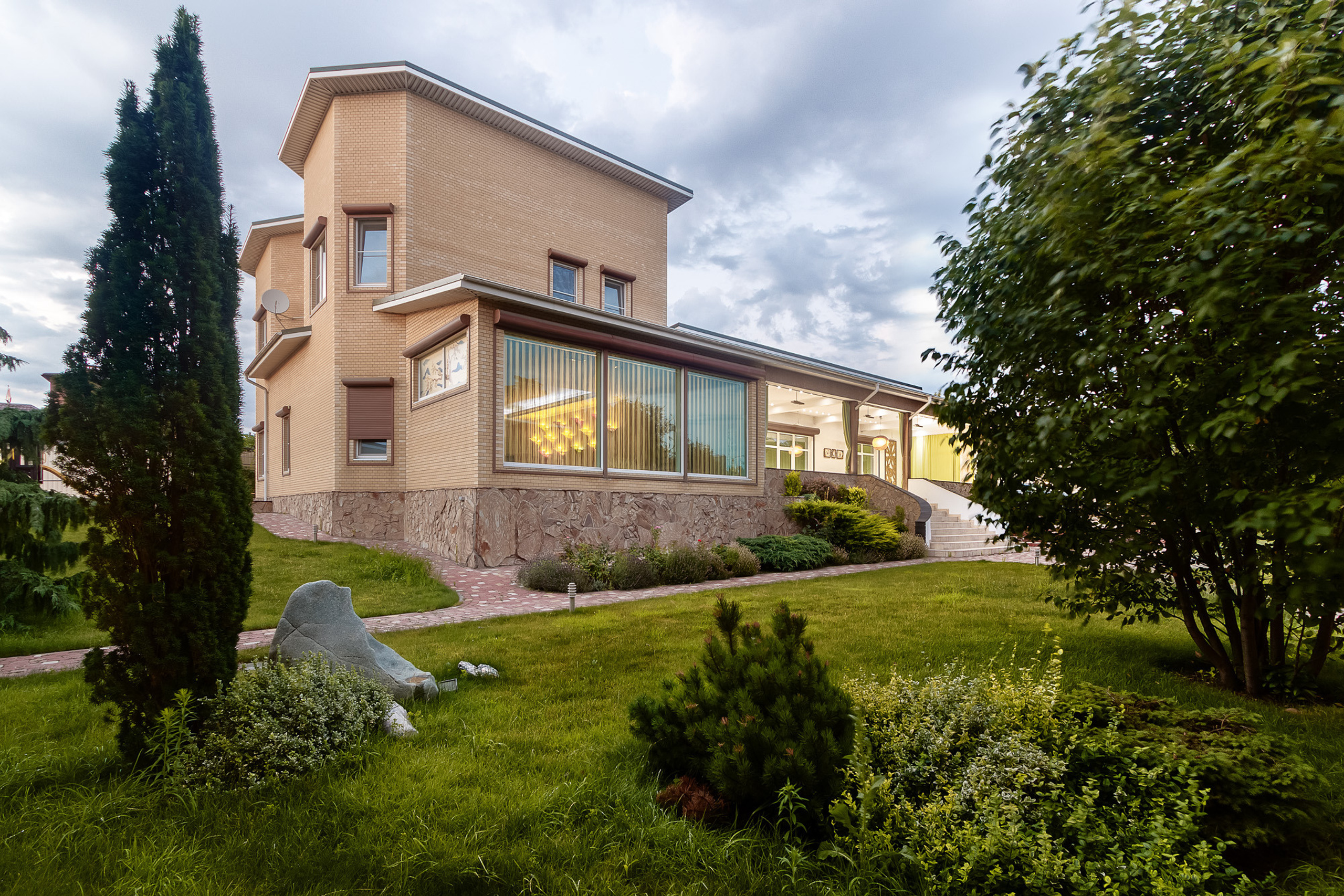 Фасад двухэтажного загородного дома с парковой зоной перед ним