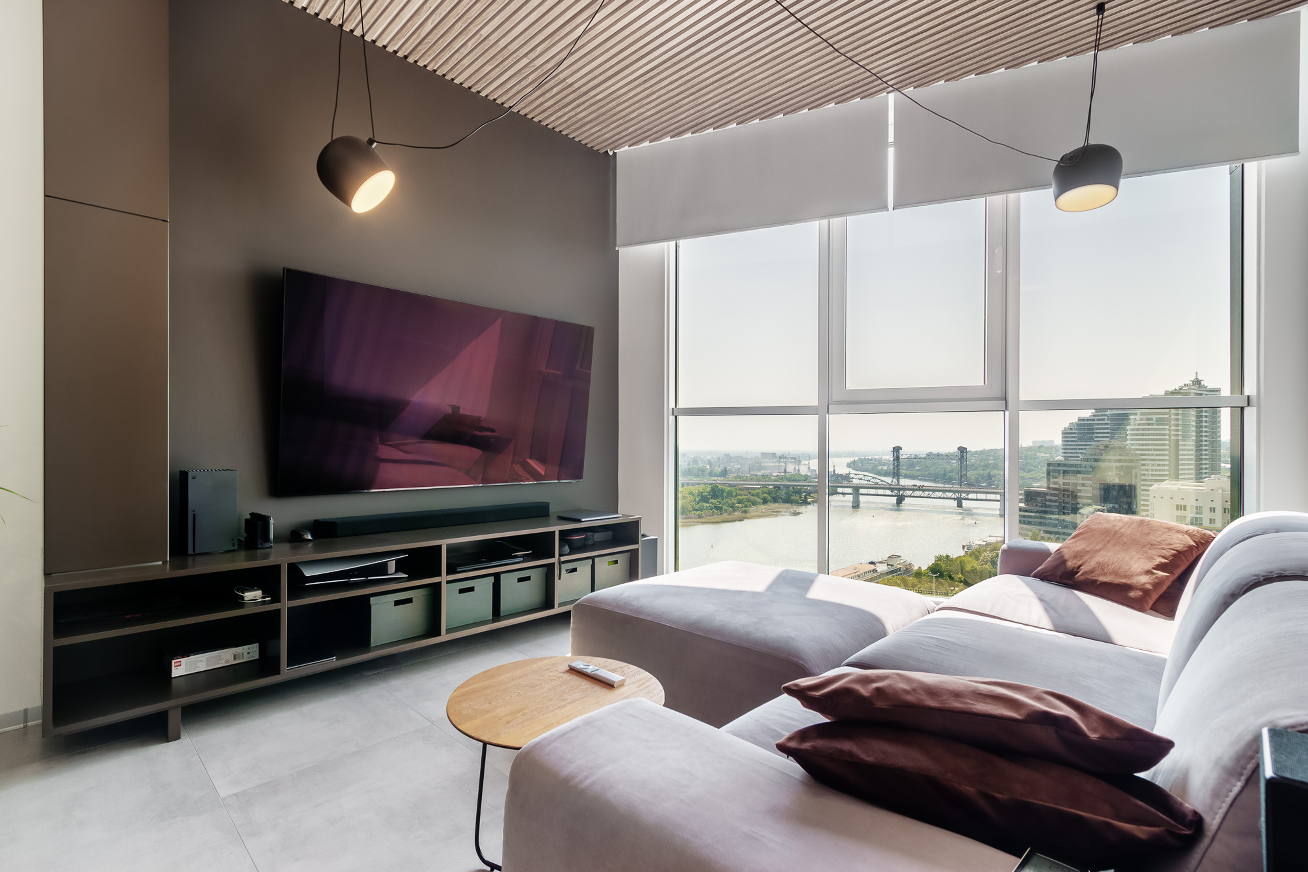 Гостиная комната с большим телевизором, диваном и панорамными окнами с видом на реку Дон в Ростове-на-Дону