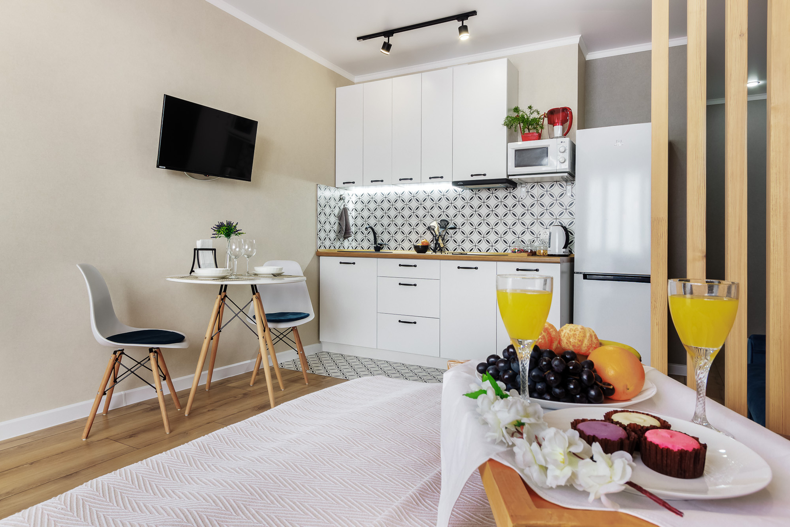 Современный интерьер уютной студии с зоной кухни и подносом на кровати