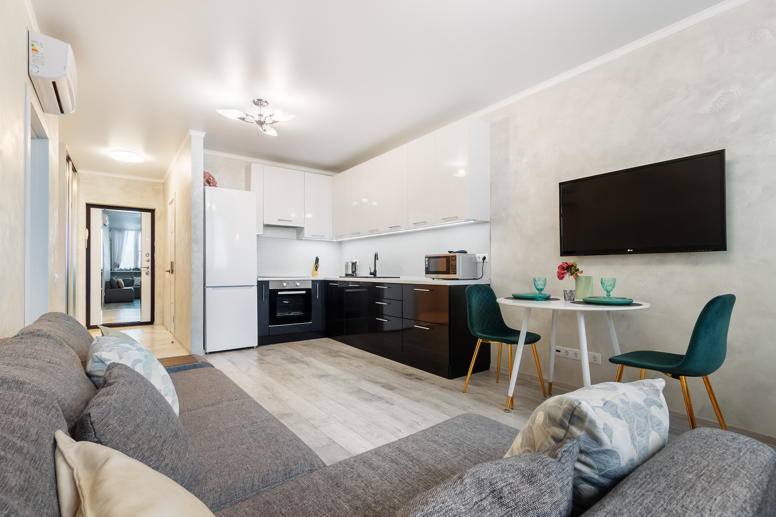 Интерьер квартиры-студии с большим серым диваном и угловой кухней