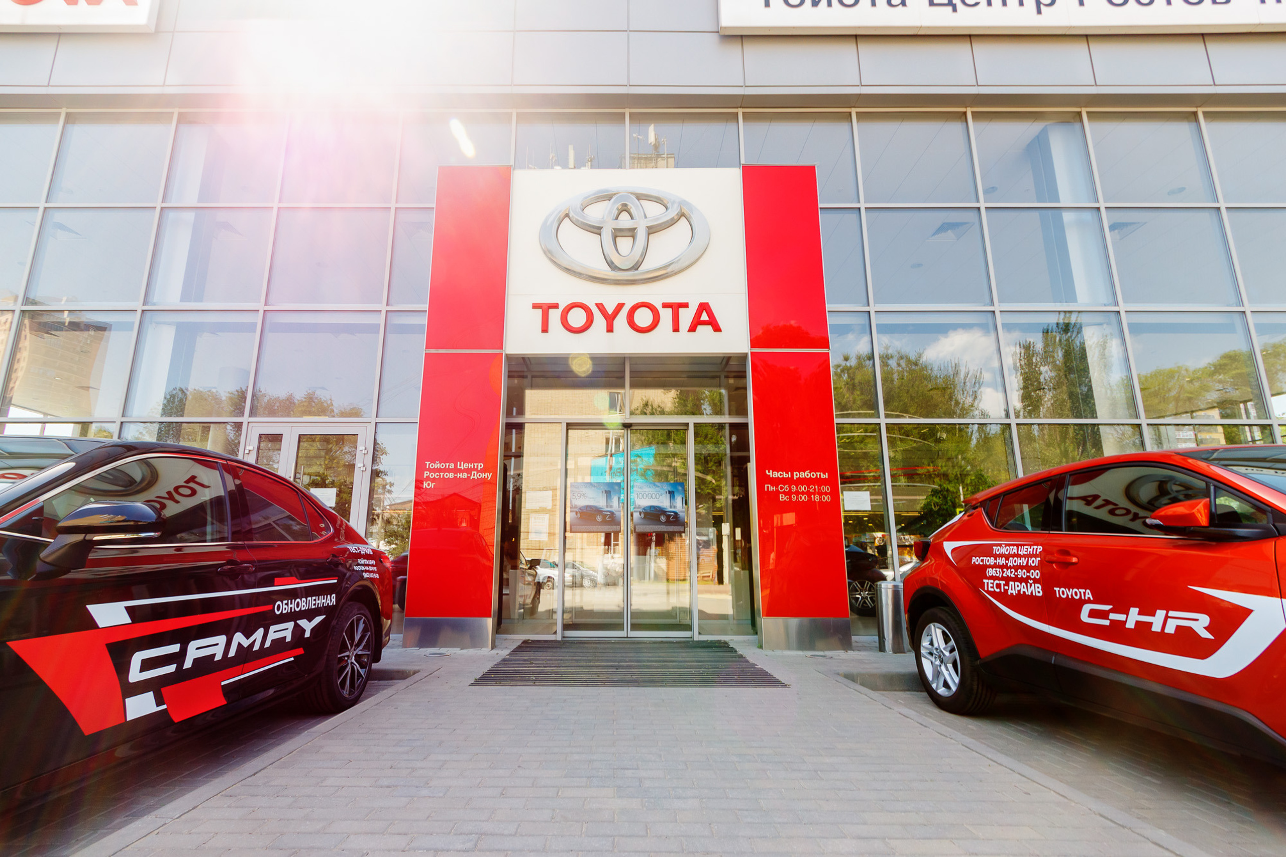 Входная группа здания автосалона с выставленными рядом автомобилями