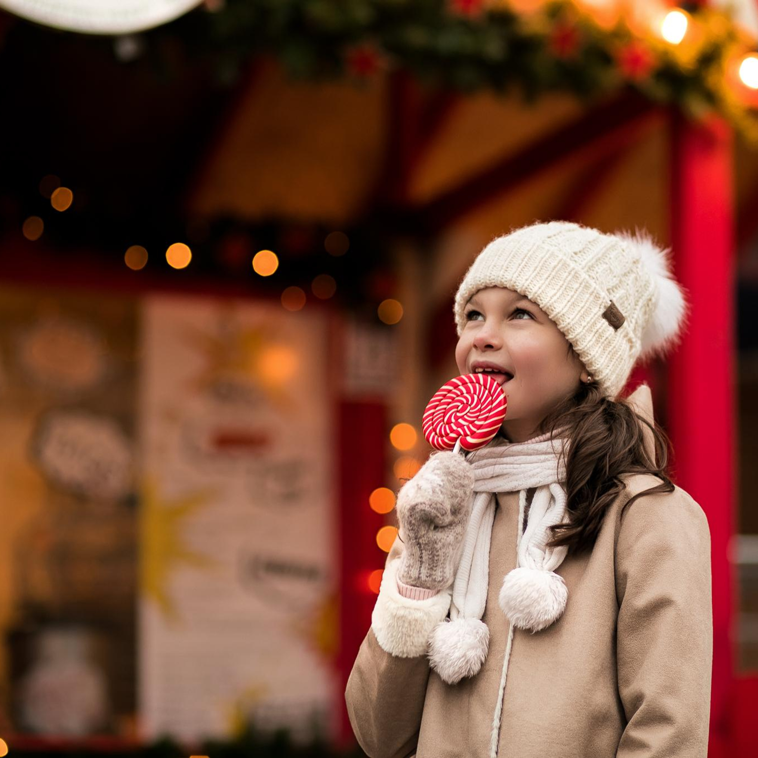 Девочка с красным леденцом на новогодней ярмарке в Санкт-Петербурге.