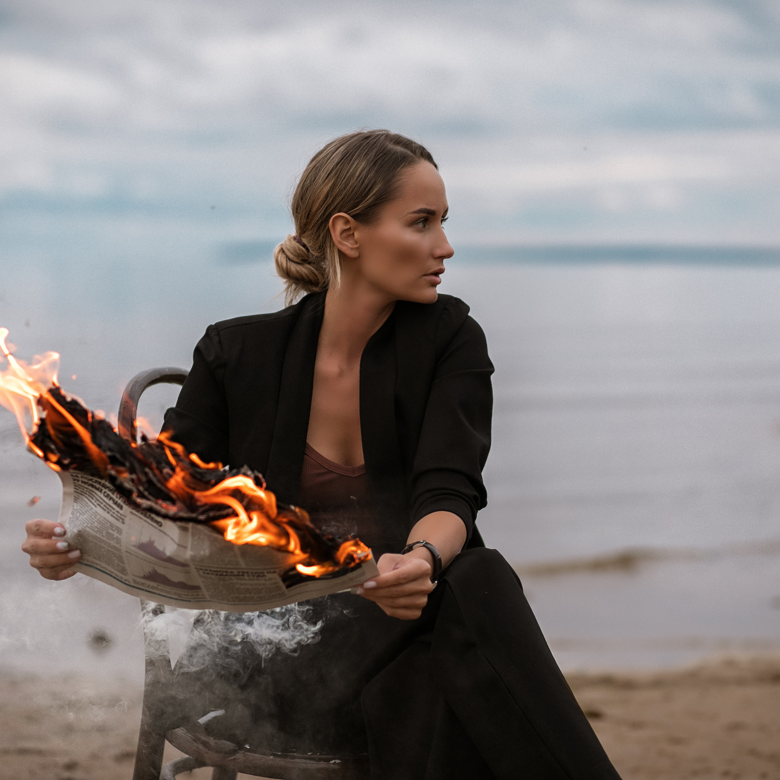 Девушка с горящей газетой, в пасмурный день на Финском заливе.