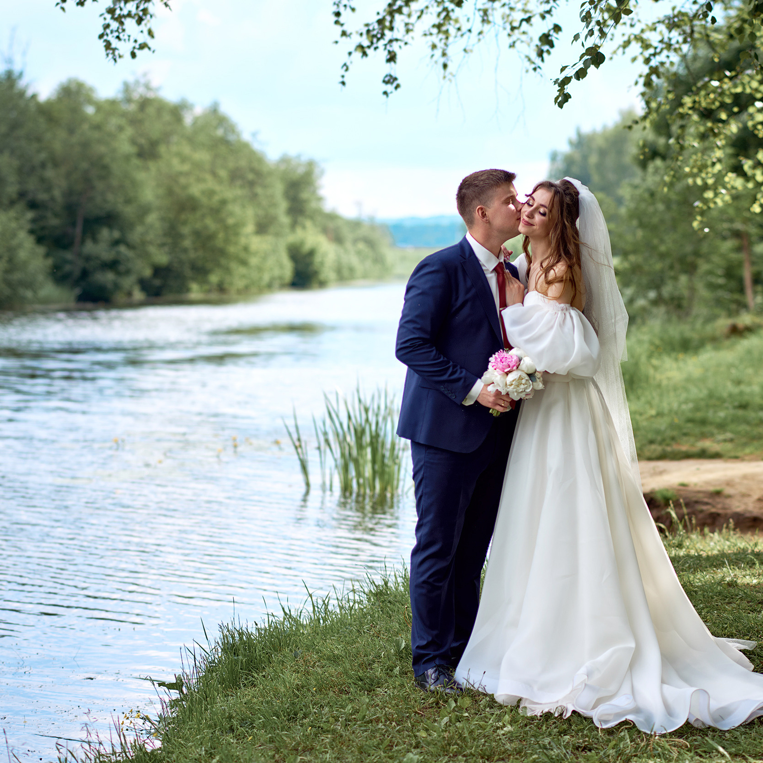 Романтический поцелуй молодоженов на фоне красивой природы