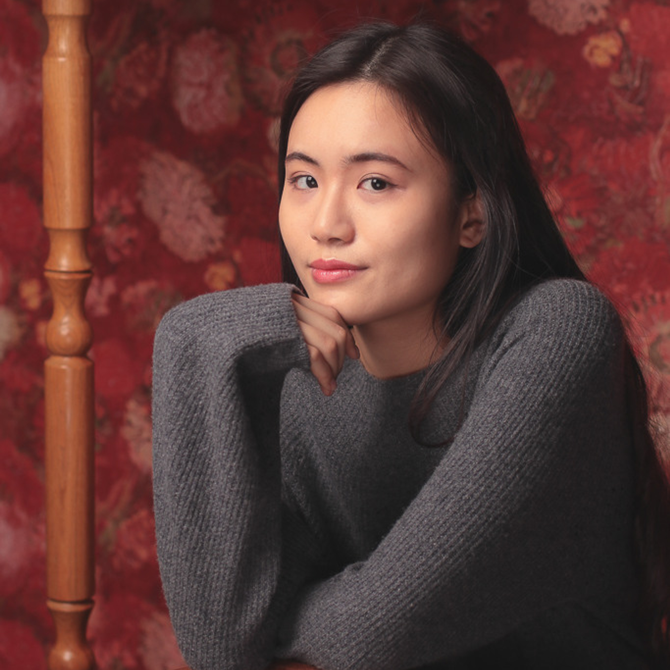 Китайская фотомодель позирует используя стул