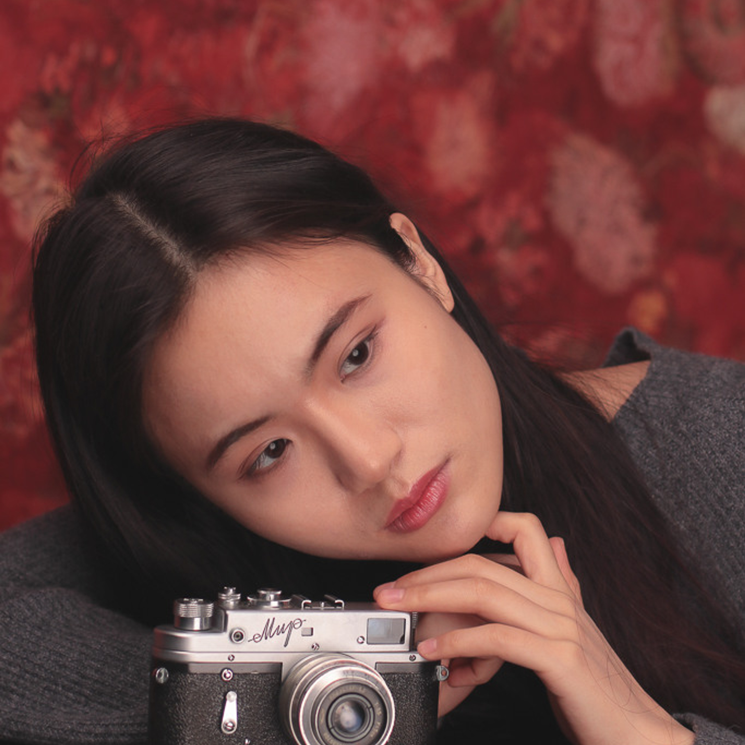 Эмоциональный портрет китайской модели позирующей с фотоаппаратом Мир