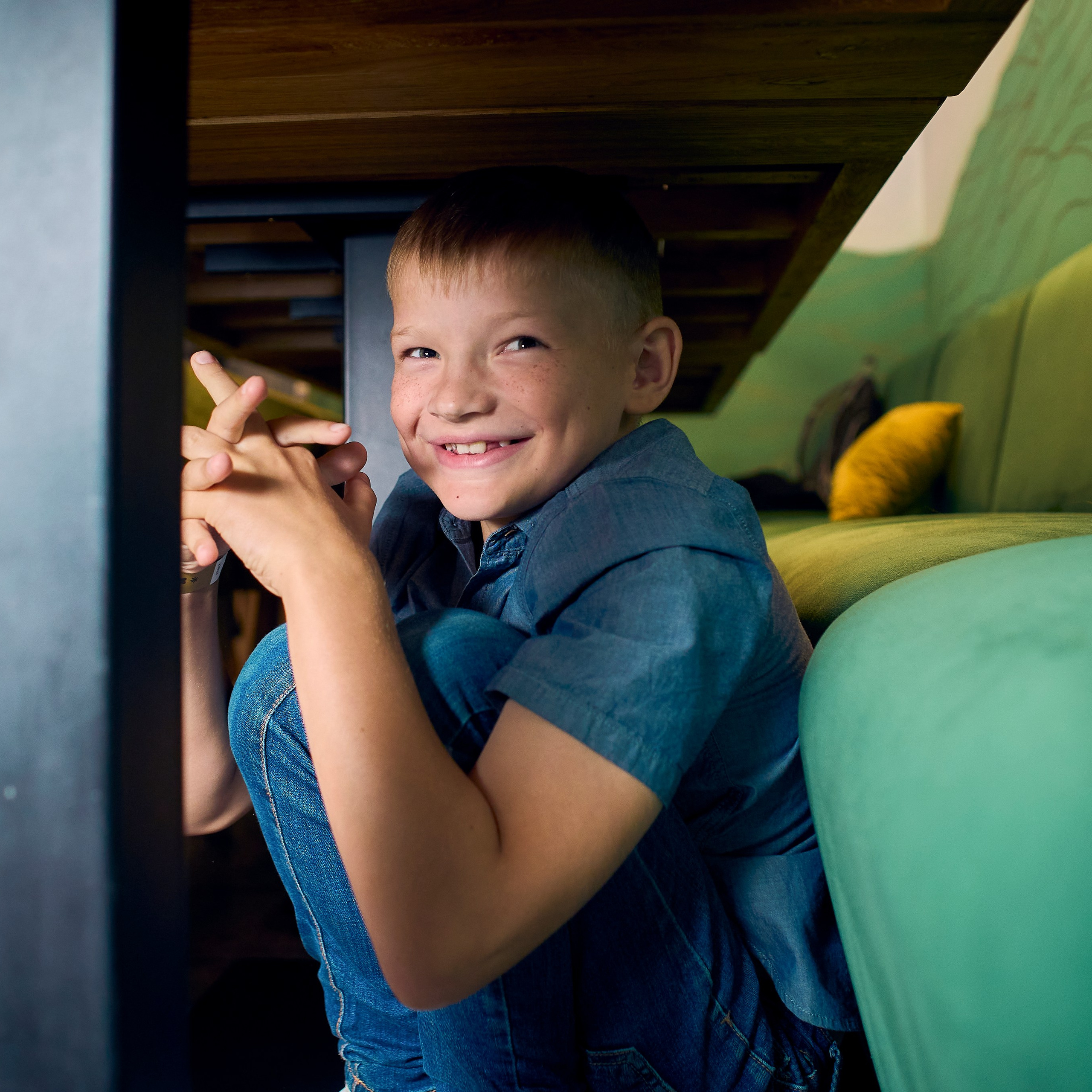 Мальчик смеется под столом