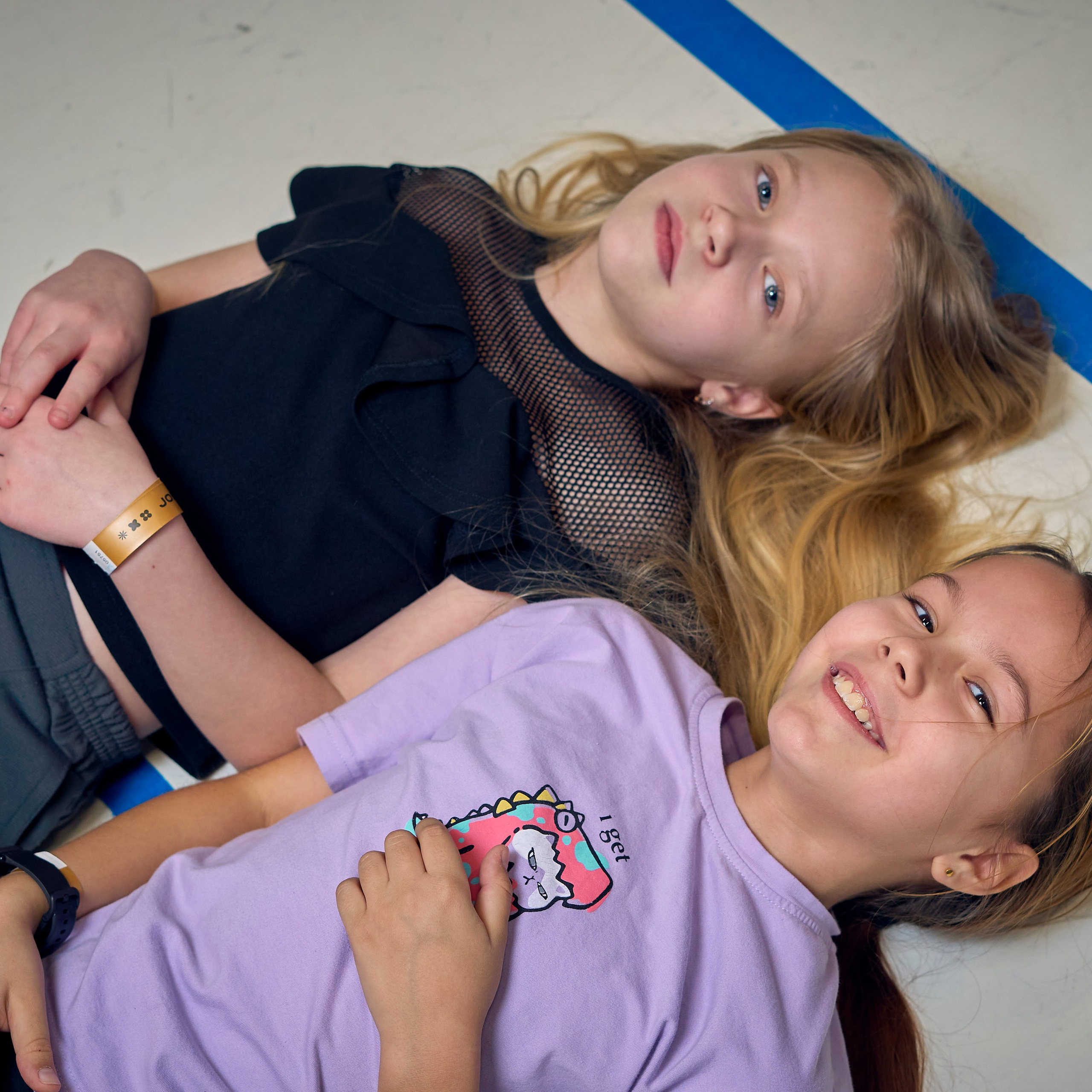 Две девочки лежат на полу и улыбаются