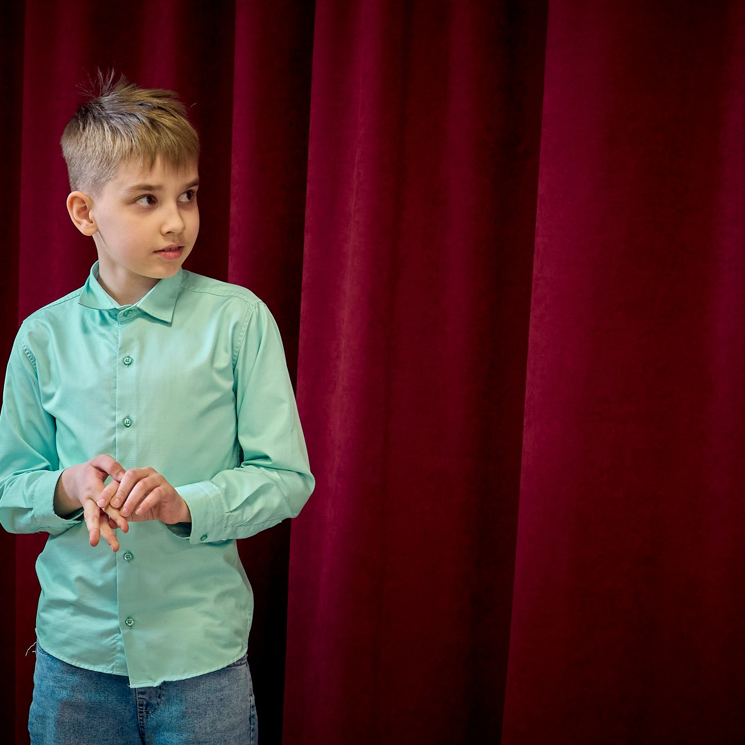Мальчик в рубашке стоит на красном фоне