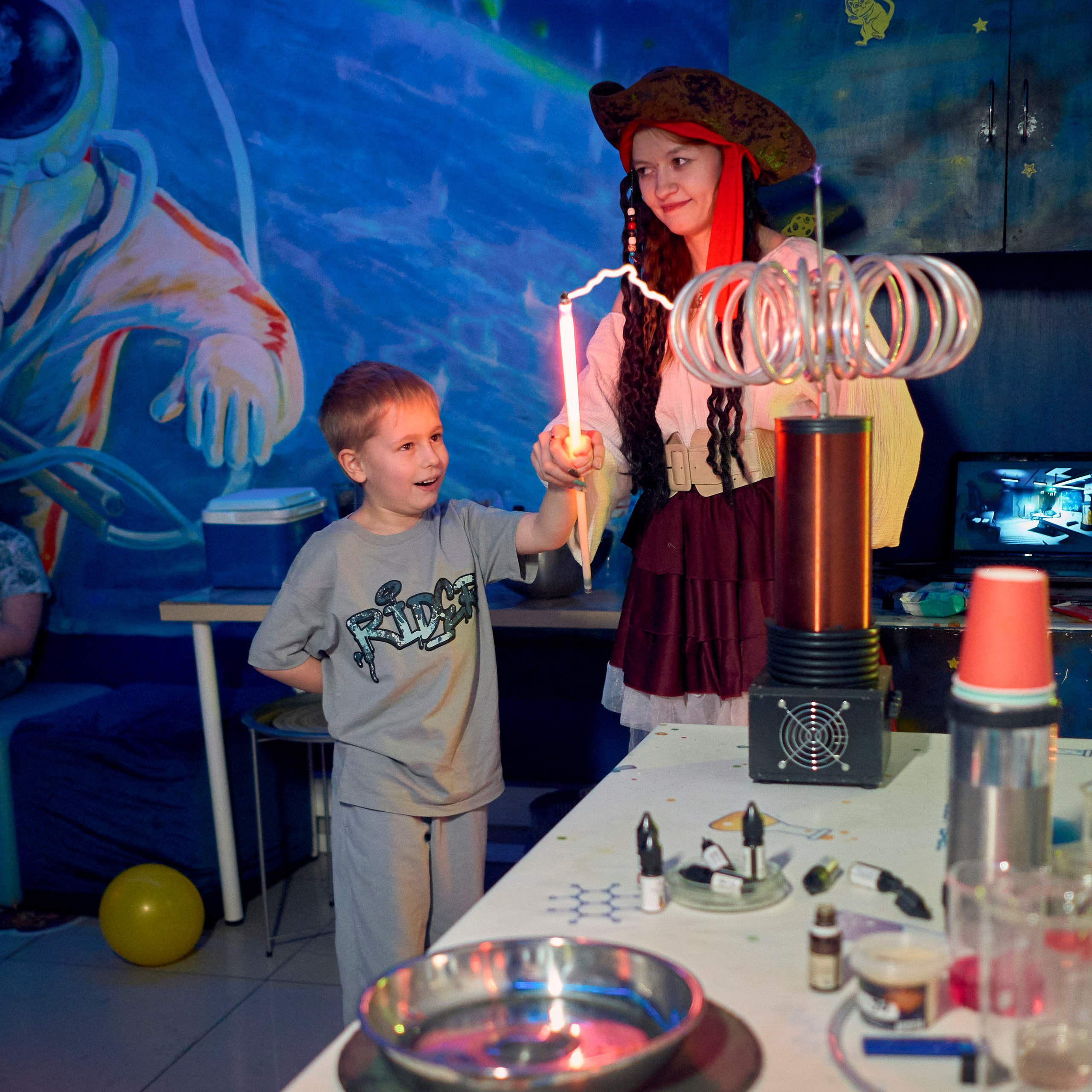 Аниматор в костюме пирата показывает катушку теслу ребенку