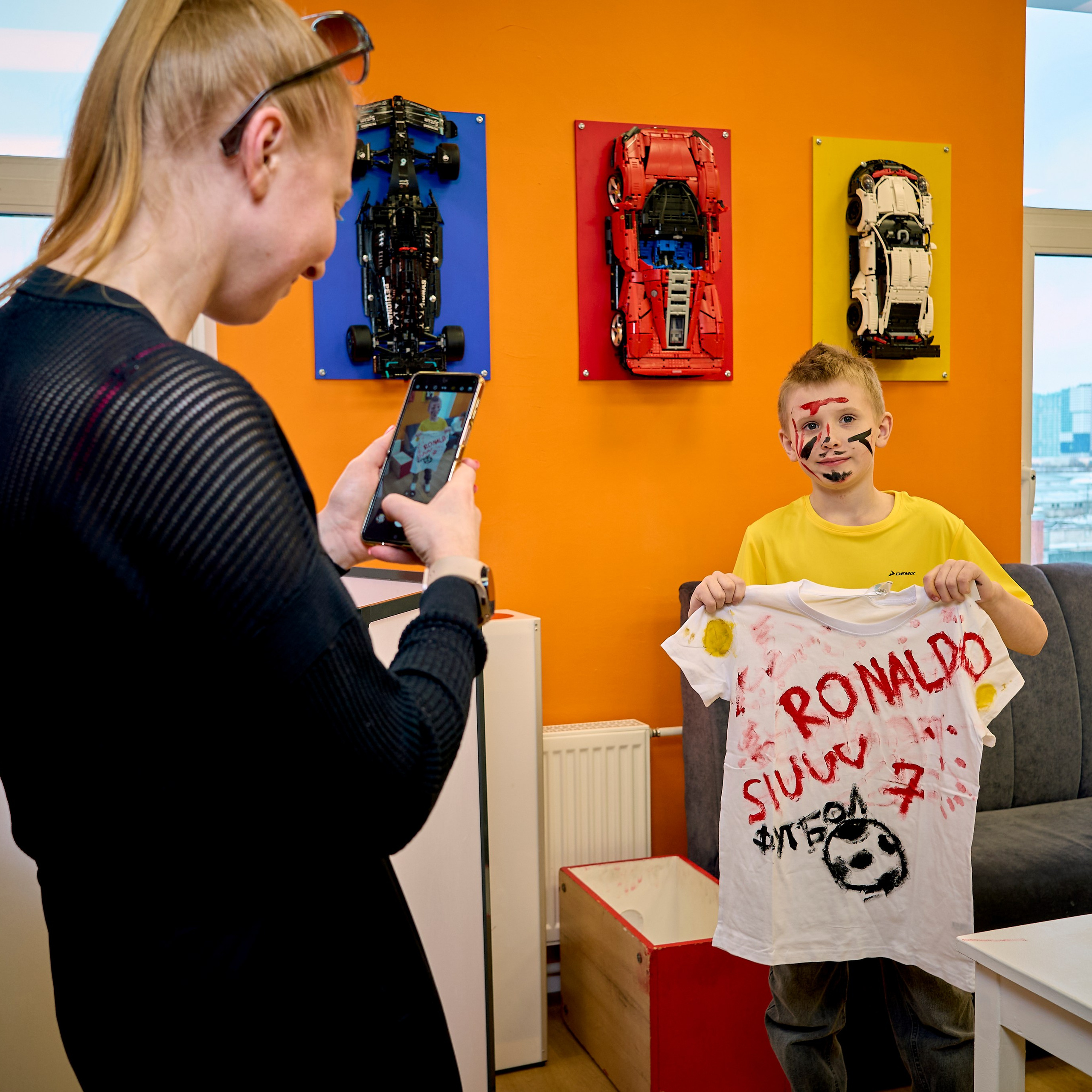 Мама фотографирует мальчика, которые сам разрисовал футболку