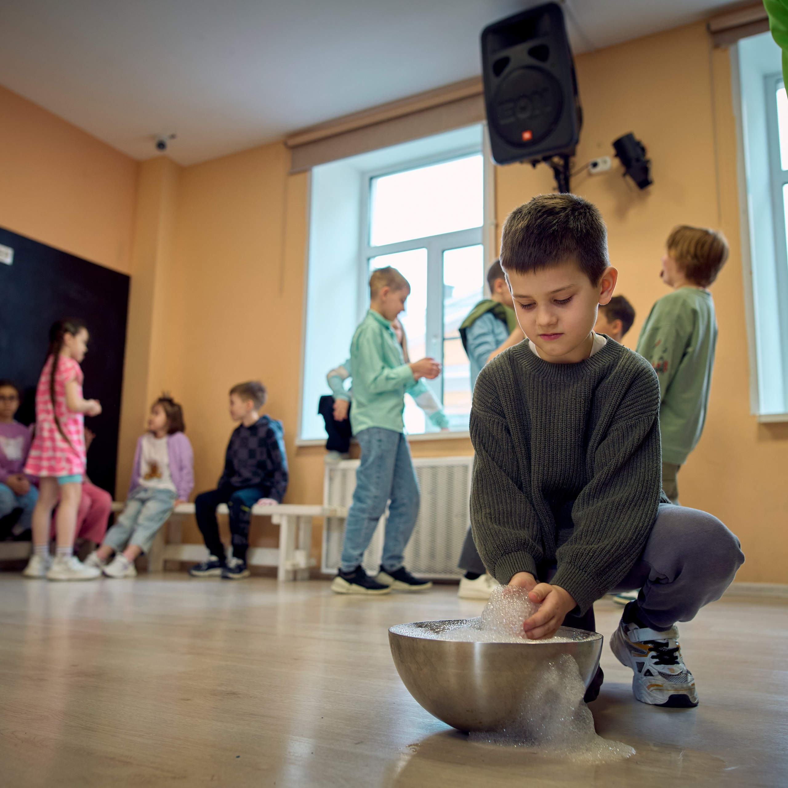 Мальчик опустил руки в миску с мыльной водой