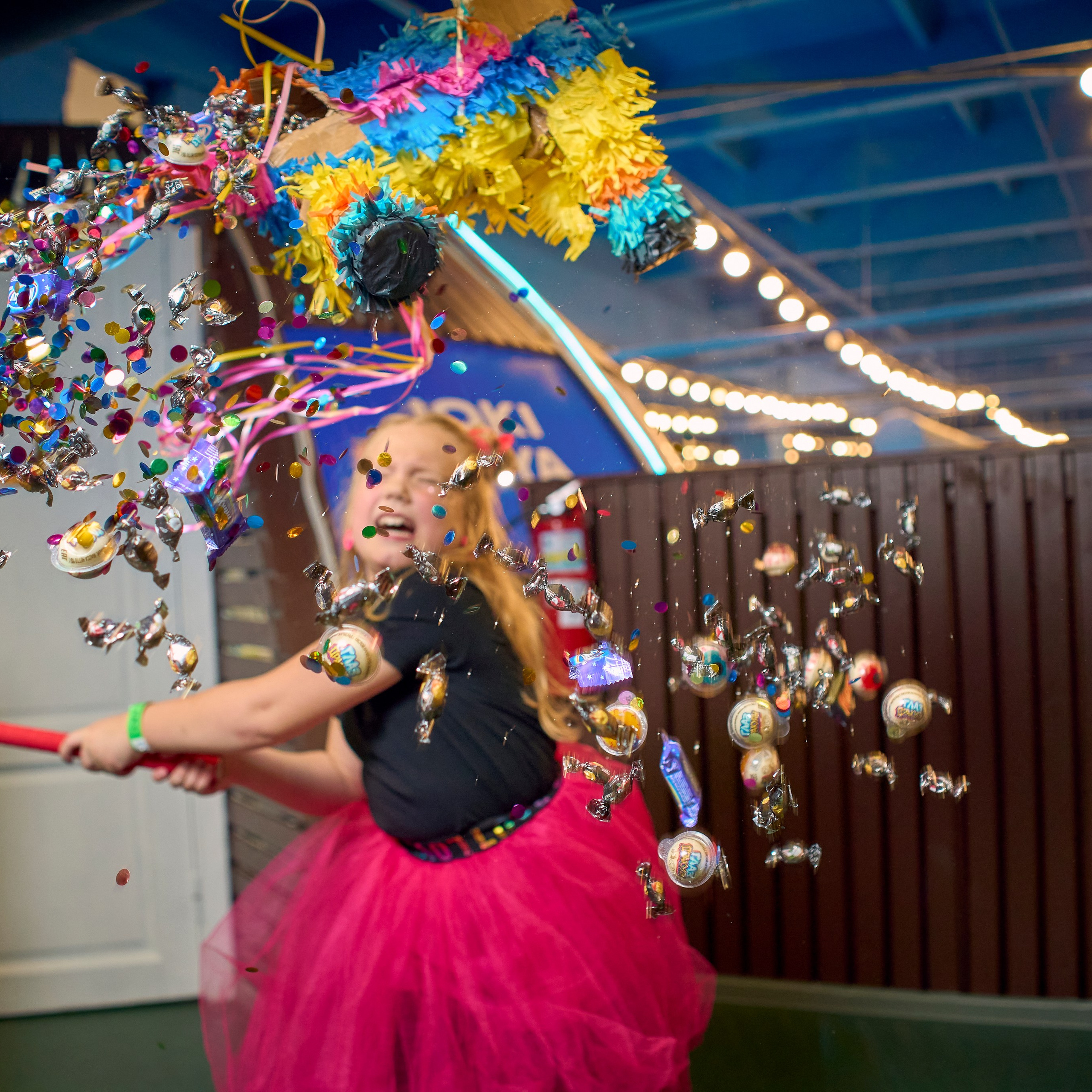 Девочка в платье разбивает пиньяту