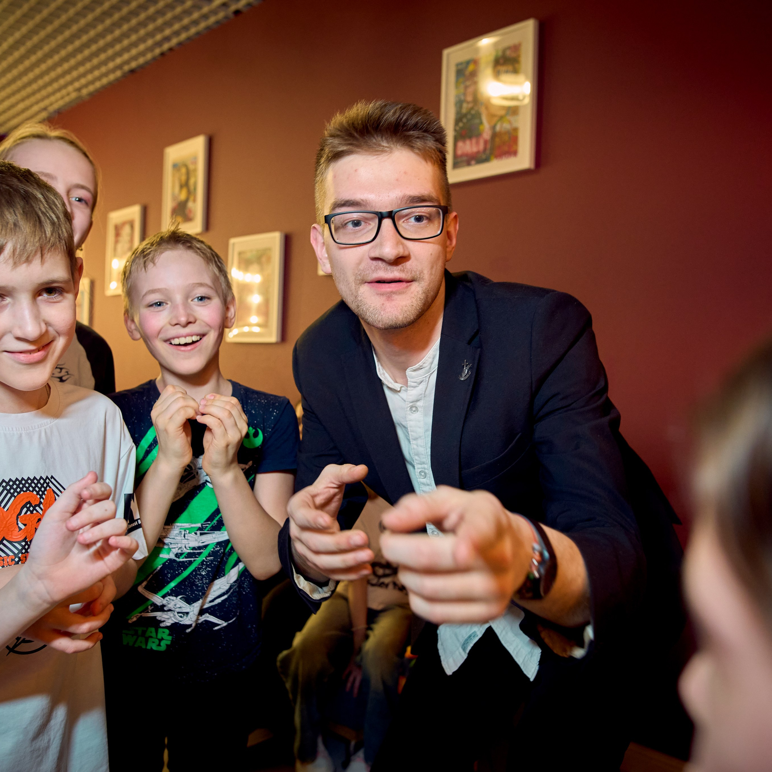 Группа детей вместе с нарядный ведущим показывают другому ребенку пальцы