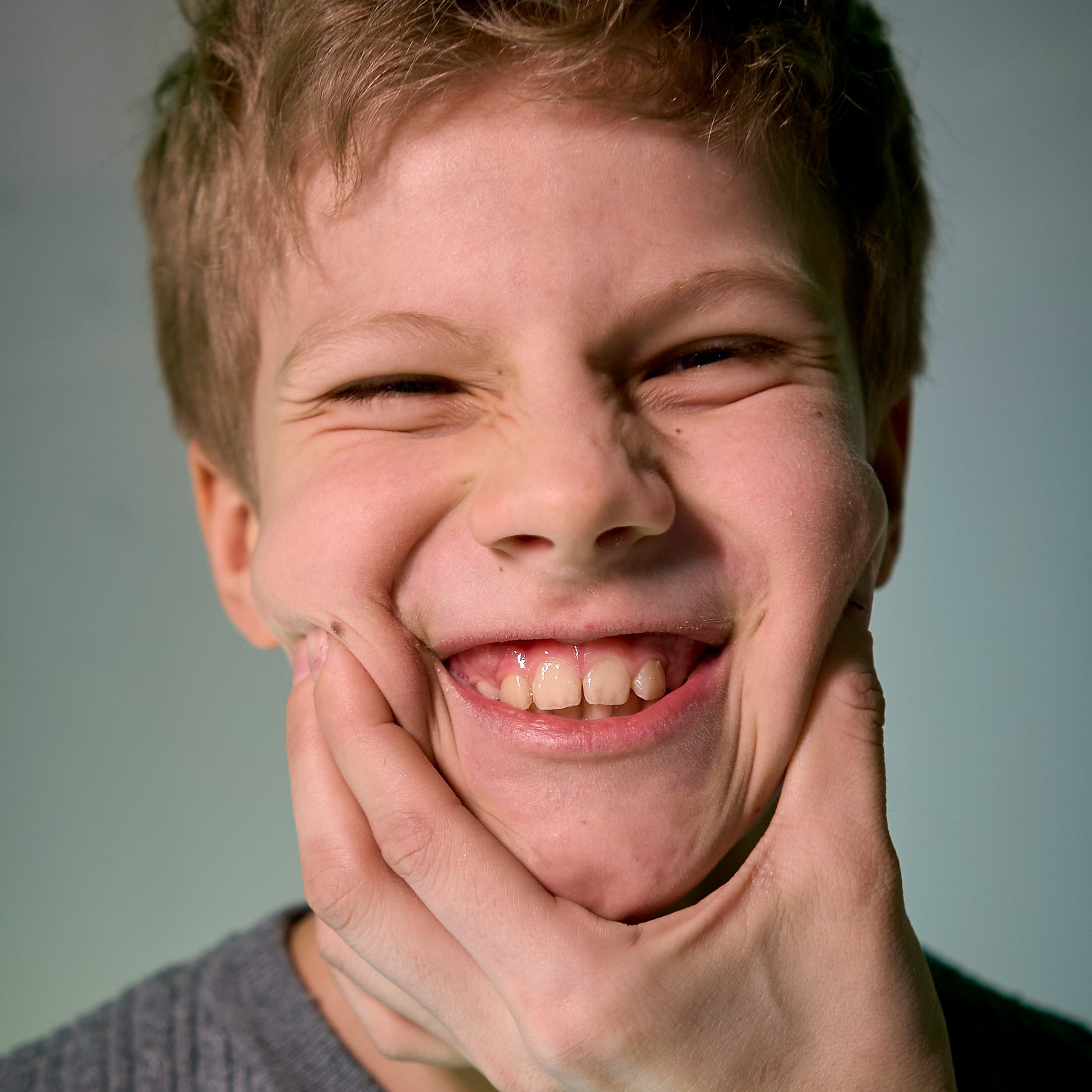 Улыбка и рука на лице у мальчика