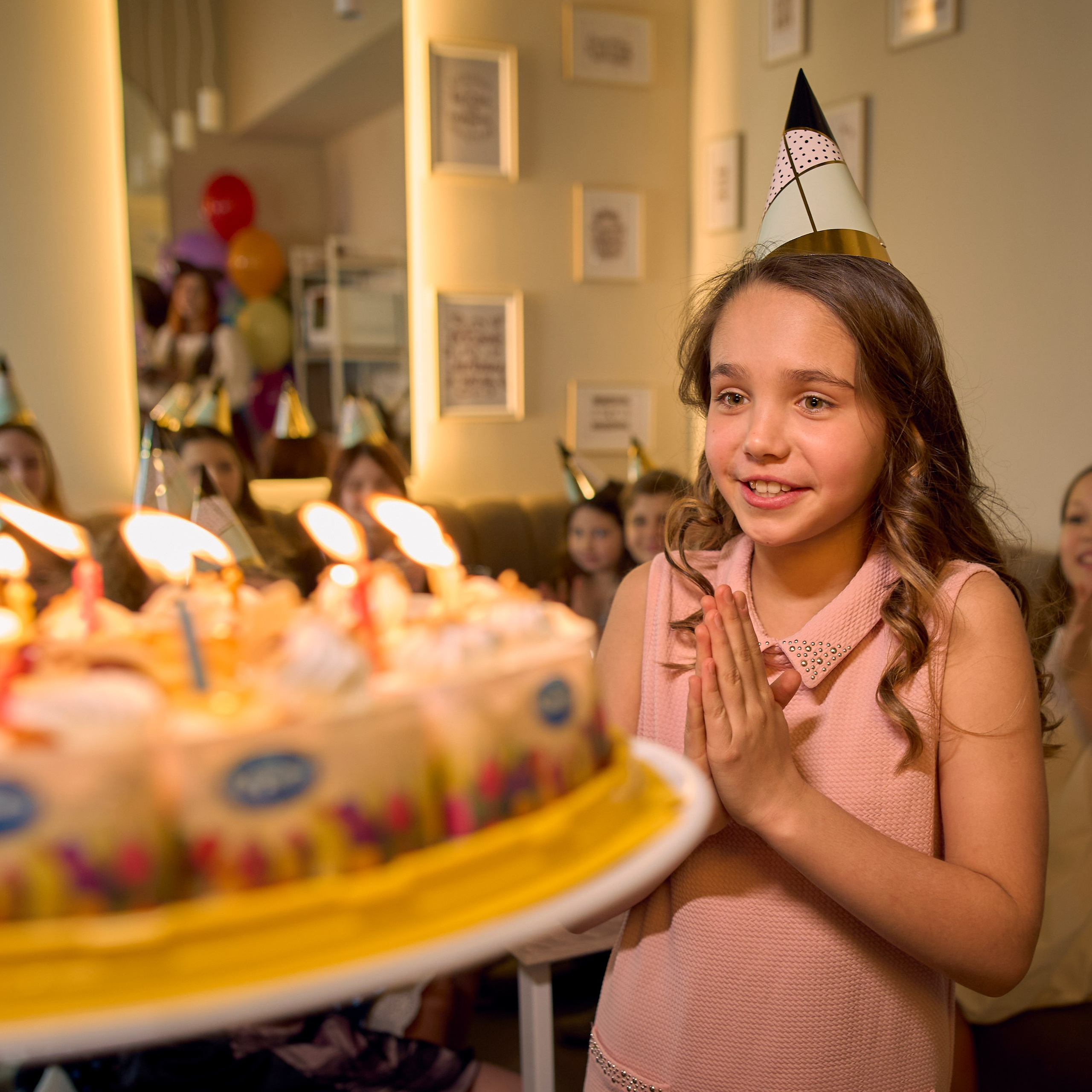 Девочка в платье задувает свечки на торте