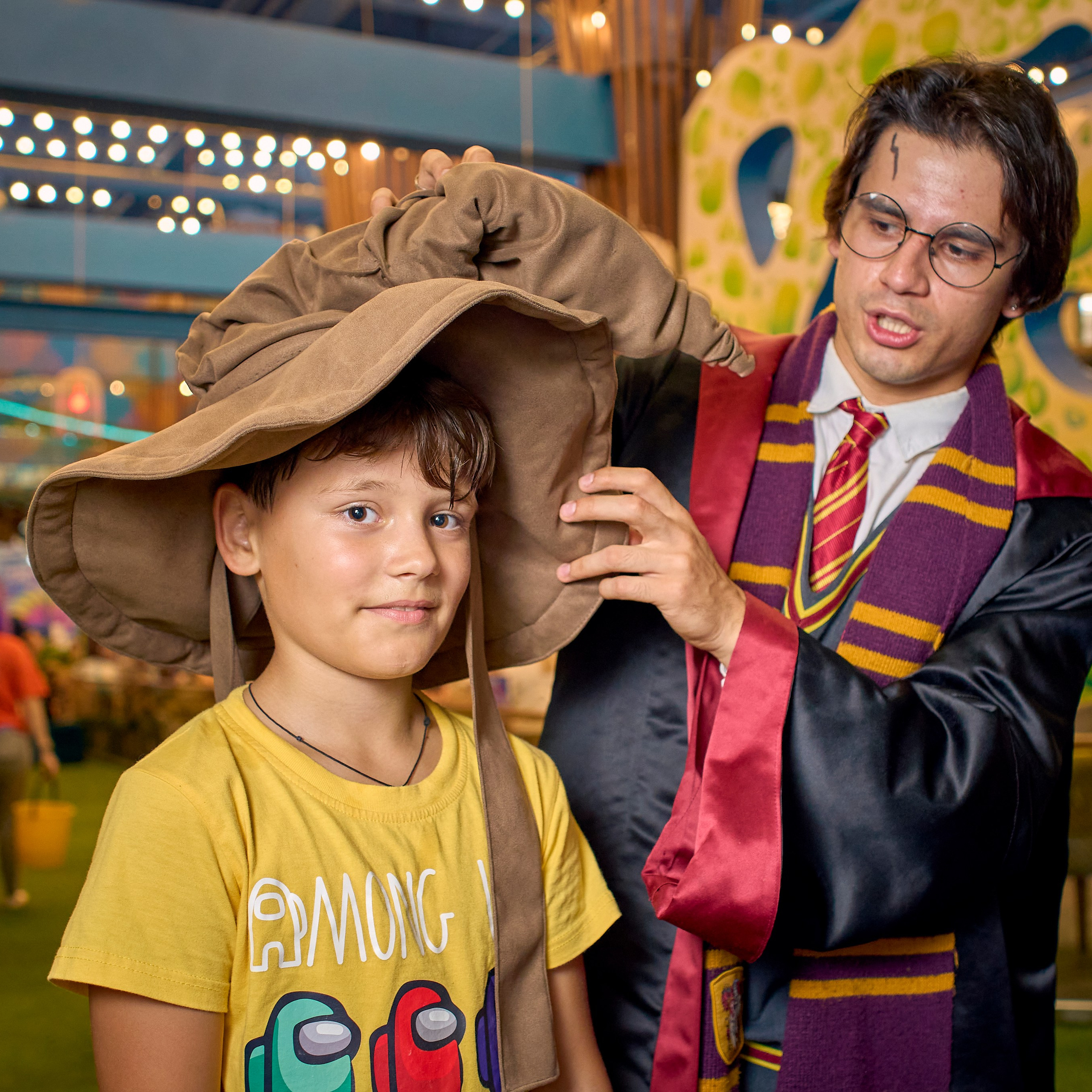 Аниматор в костюме Гарри Поттера посвещает с помощью шляпы ребенка