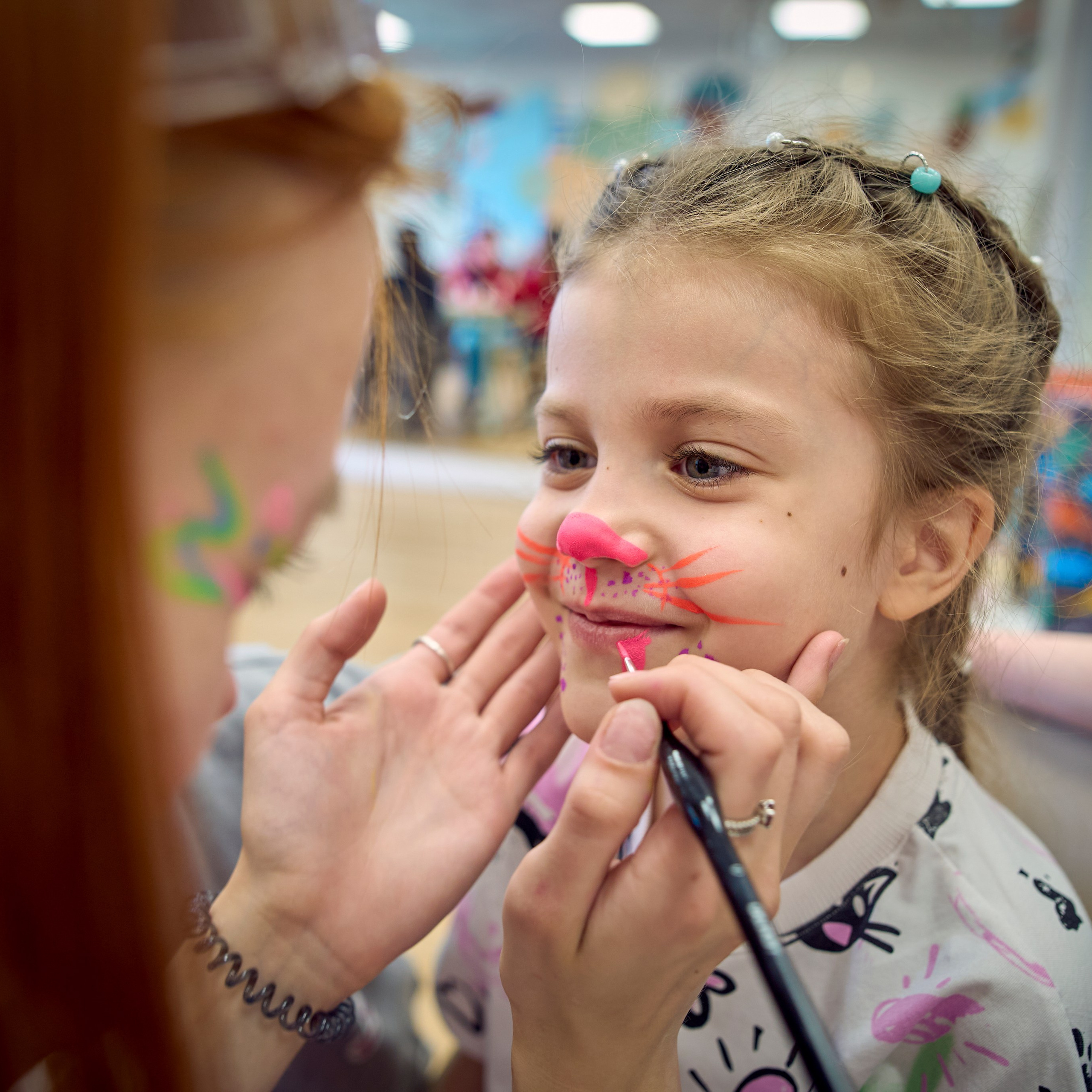 Аниматор рисует на лице ребенка аквагрим