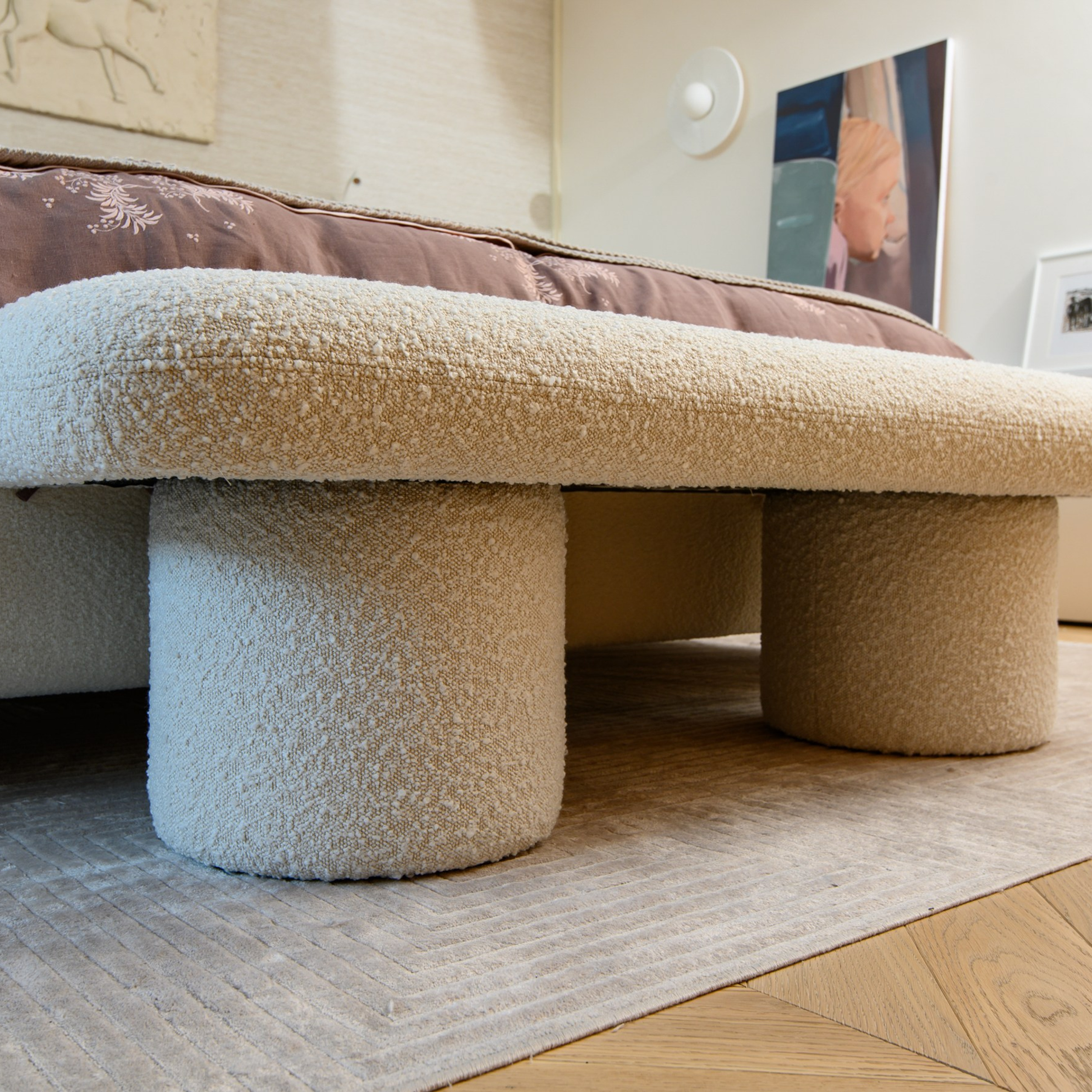 Компаньоном кровати выступает эффектная банкетка обтекаемой формы в обивке букле.