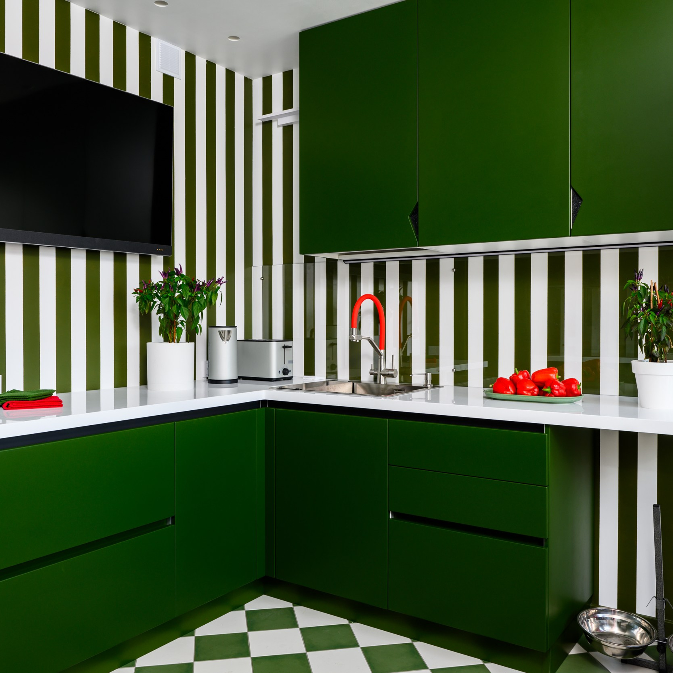 Зеленый оттенок фасадов из МДФ называется «Амазония» и практически один-в-один совпадает с полосками на стенах. Дверцы на петлях с доводчиками, верхние шкафчики декорированы металлическими вставками цвета «вулканический чугун».  