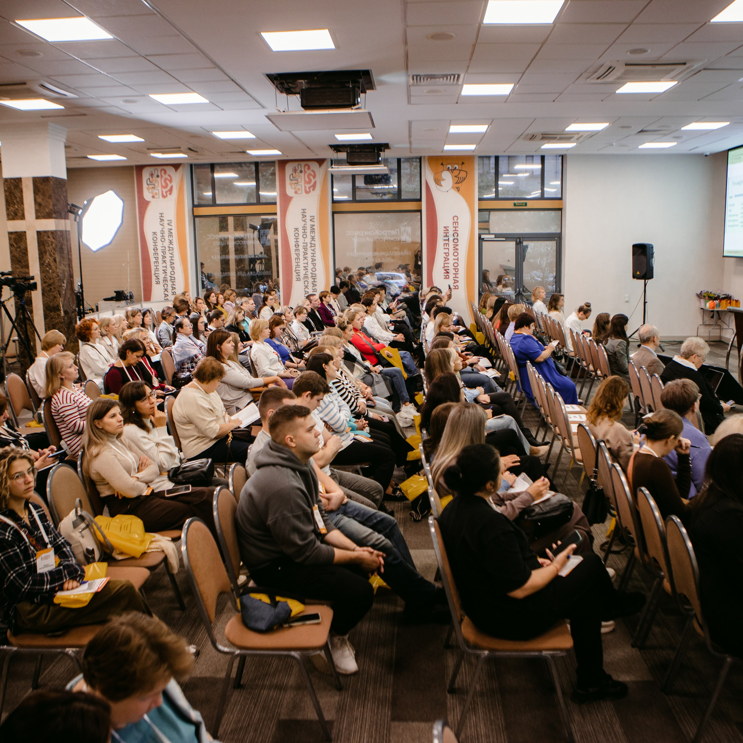 Фото с конференции по сенсомоторной интеграции. Организатор "Сова нянька". На фото панорама зрительного зала, видно гостей и спикера.