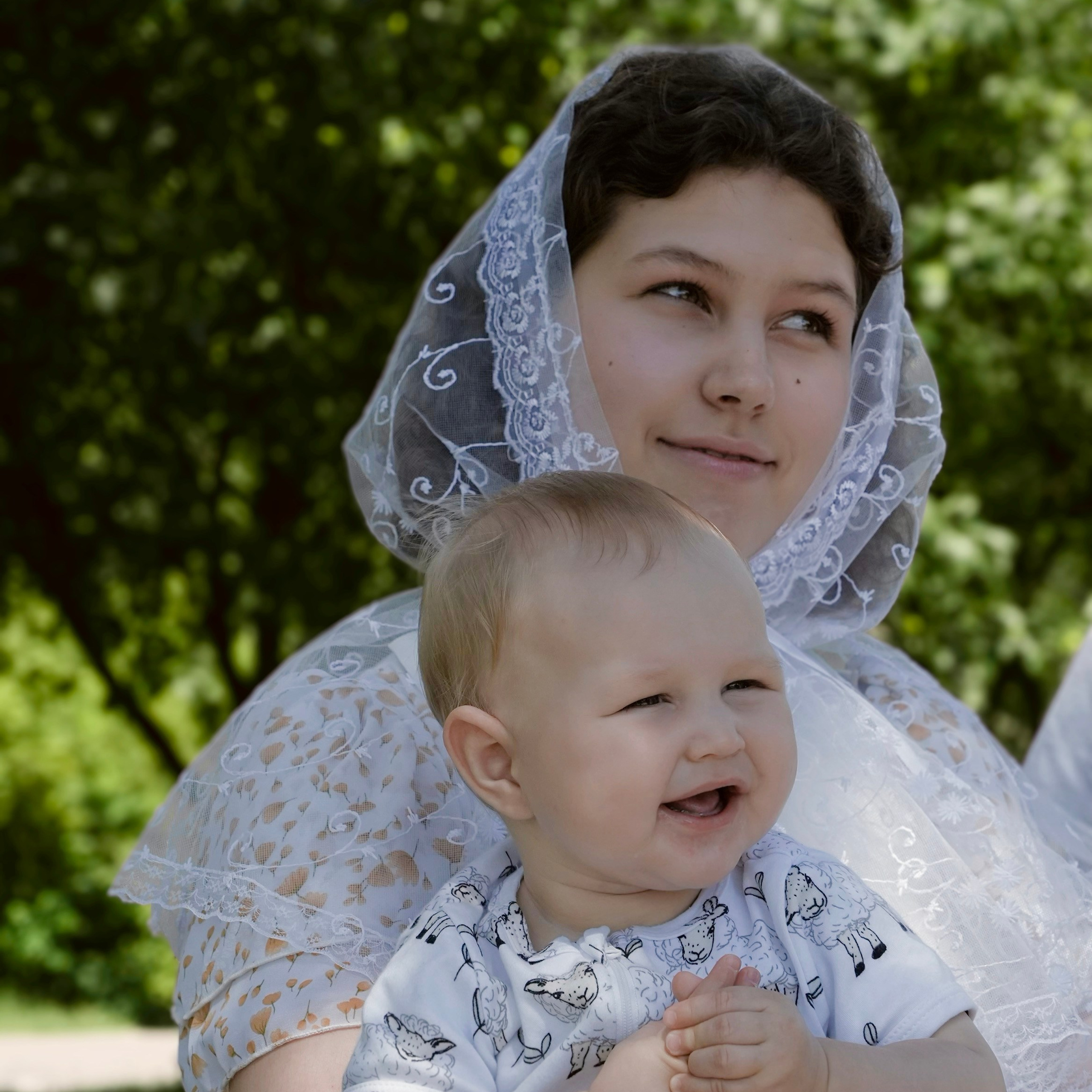 Крещение, малыш улыбается на руках у крестной мамы