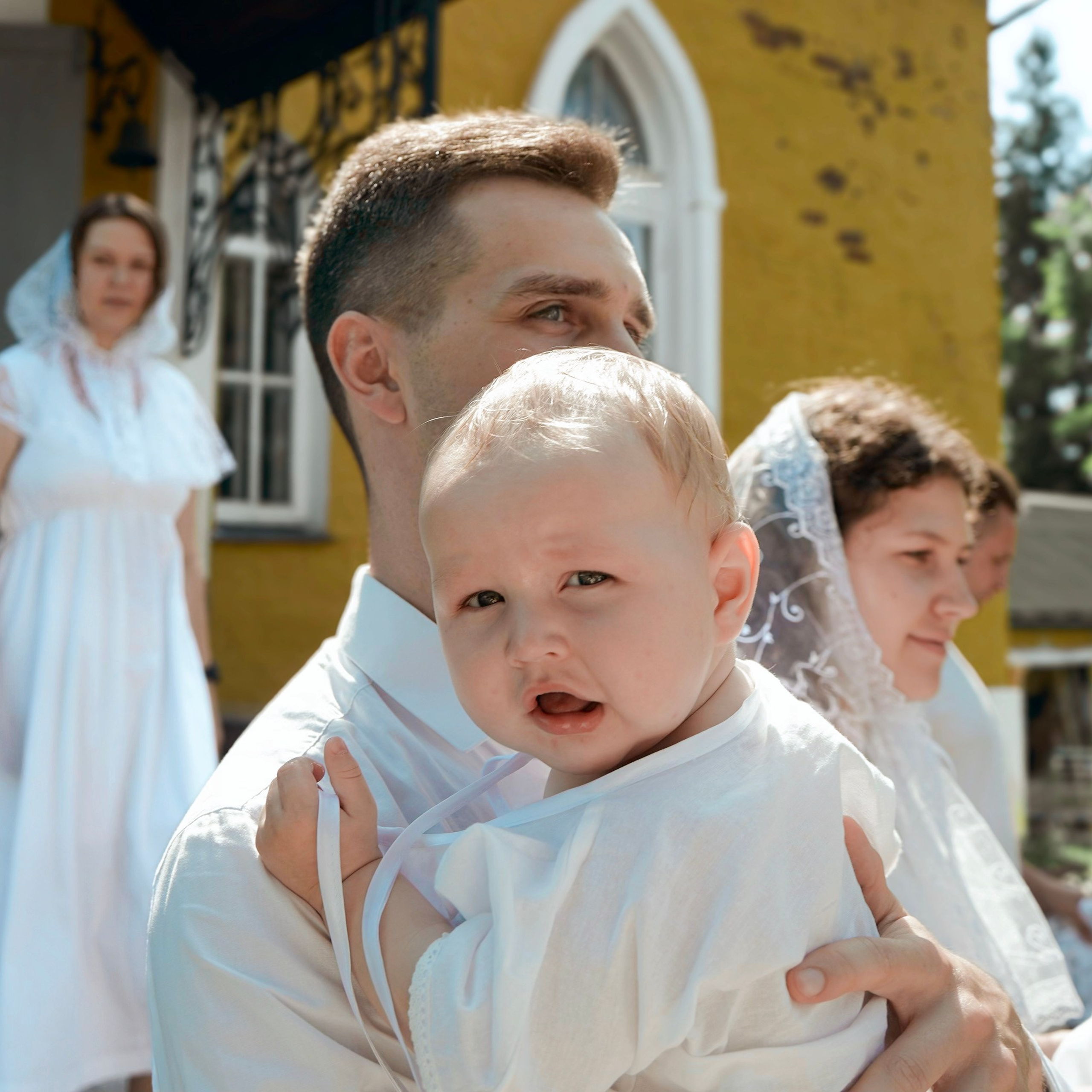 Крещение, малыш смотрит в камеру, находясь на руках у крестного