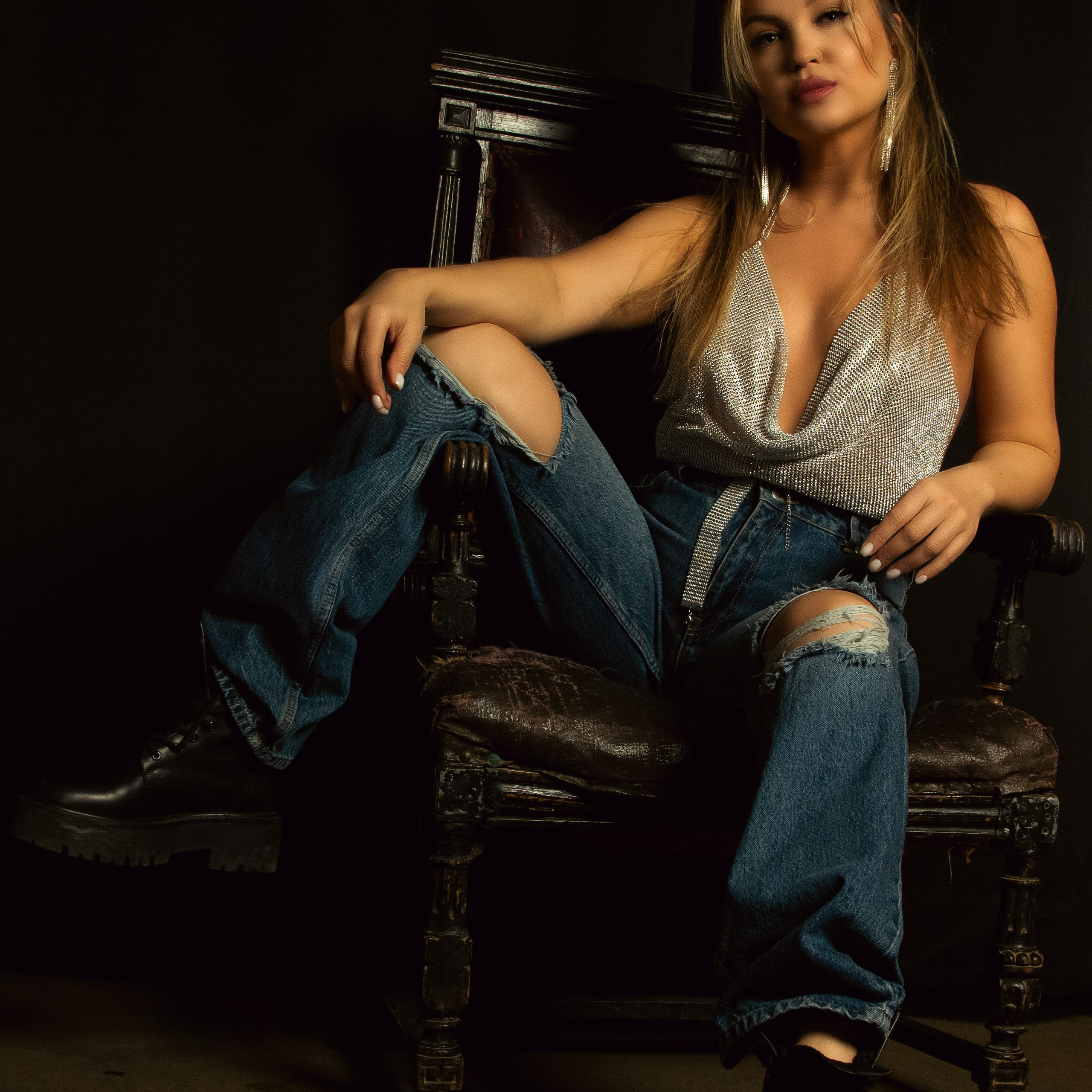Фото раскованной женщины на стуле в рваных джинсах