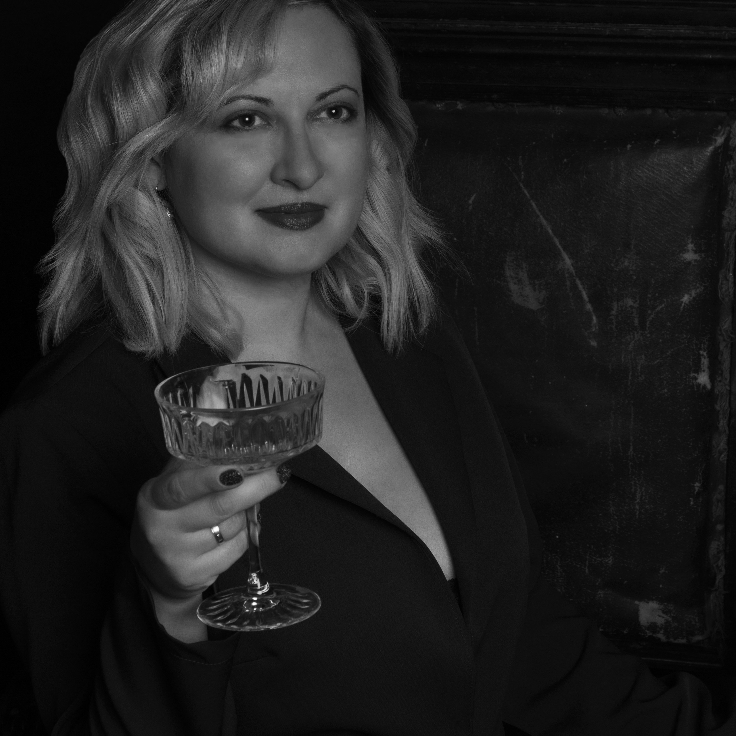 Черно-белое фото женщины в костюме с бокалом