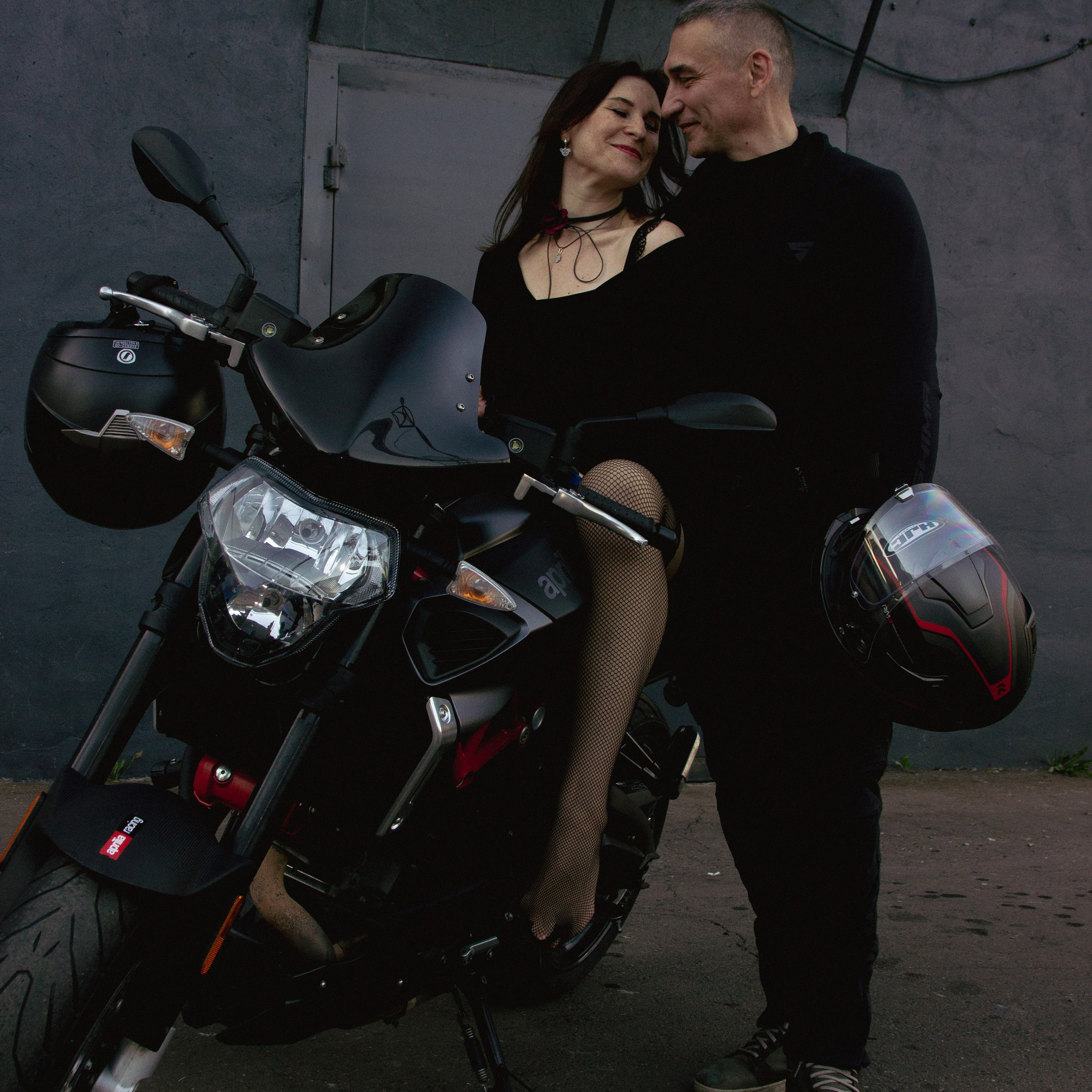 Фото пары смотрящей друг на друга на мотоцикле и держа в руках шлем