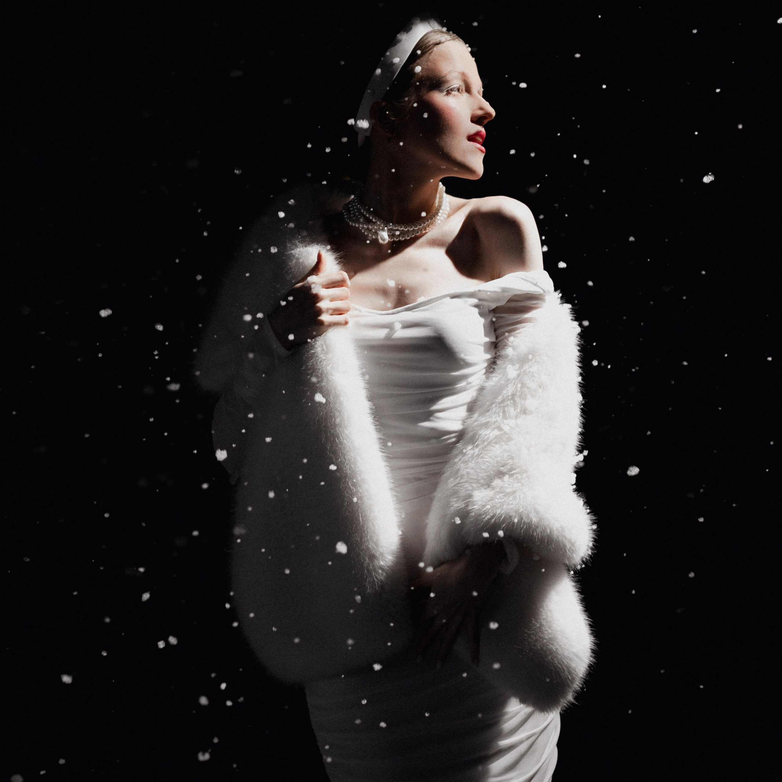 Новогодняя студийная фотосессия в Новосибирске — женщина в белом платье и меховой накидке наслаждается снегопадом