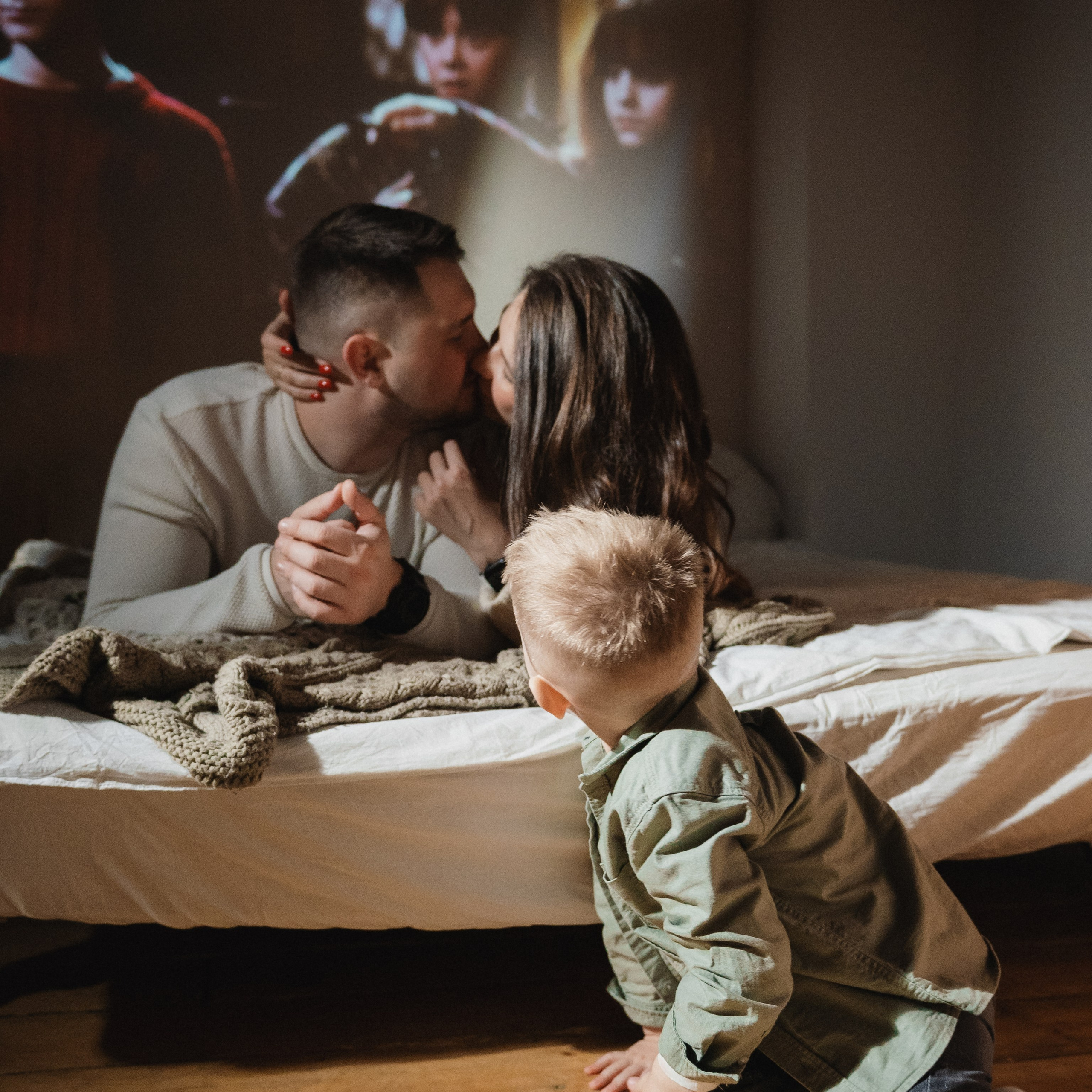 Семейная фотосессия в Новосибирске — пара с ребёнком на кровати смотрит фильм в новогодней уютной атмосфере